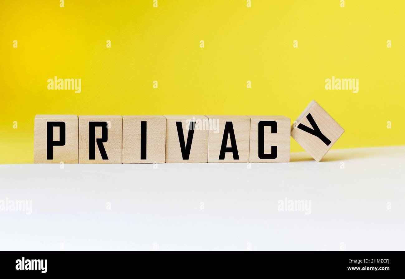 Parola di privacy su cubo di legno e sfondo bianco e giallo. Foto Stock