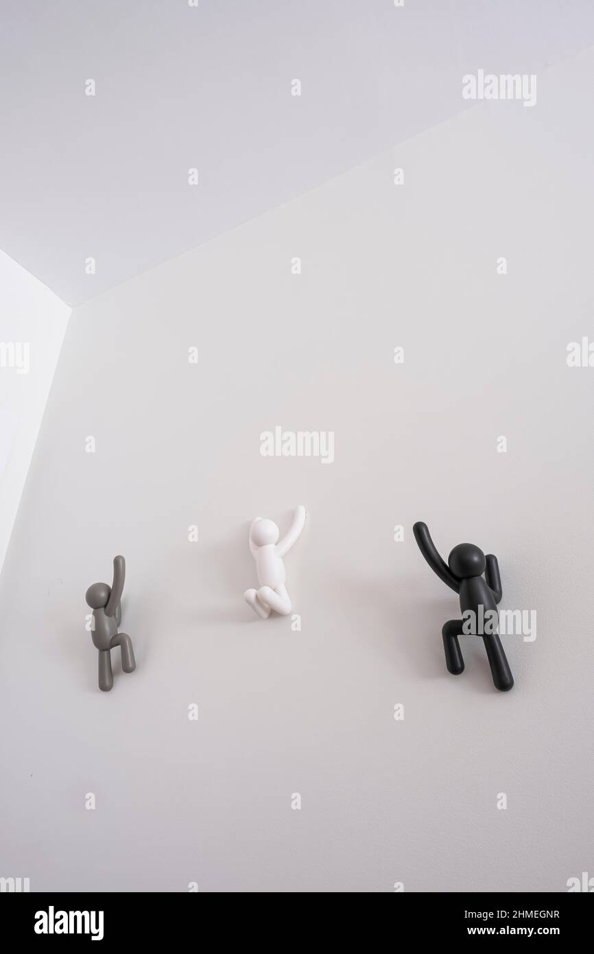 3 marionette bianche e grigie nere 3D che si arrampicano su un muro bianco, concetto di miglioramento di sé, aiutare a vicenda, messaggio di uguaglianza e di non discriminazione Foto Stock