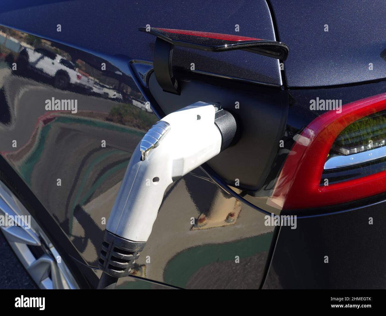 Primo piano del cavo di ricarica collegato a un veicolo elettrico in fase di ricarica. Foto Stock