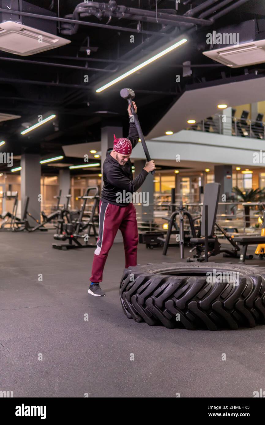 Un uomo colpisce una ruota di mazza in forma fisica, il concetto di un mazza maschile sana stile di vita martello attivo colpo martello, per la forza muscolare in atleta A. Foto Stock