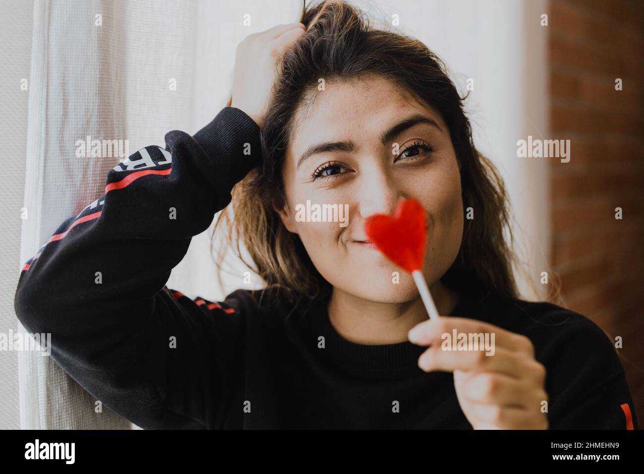 Donna latina innamorata di un lecca in mano a forma di cuore. San Valentino Foto Stock