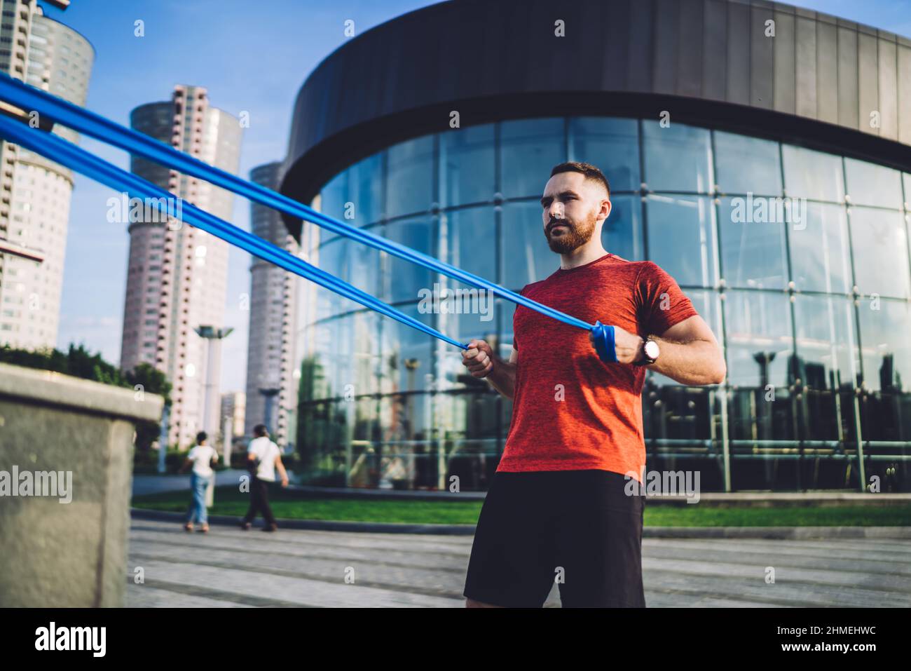 Atleta maschile concentrato che fa esercizio con banda di resistenza Foto Stock