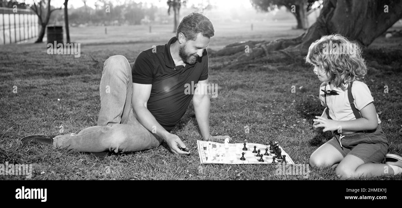 padre e figlio giocano a scacchi sull'erba nel parco estivo, a scacchi Foto Stock