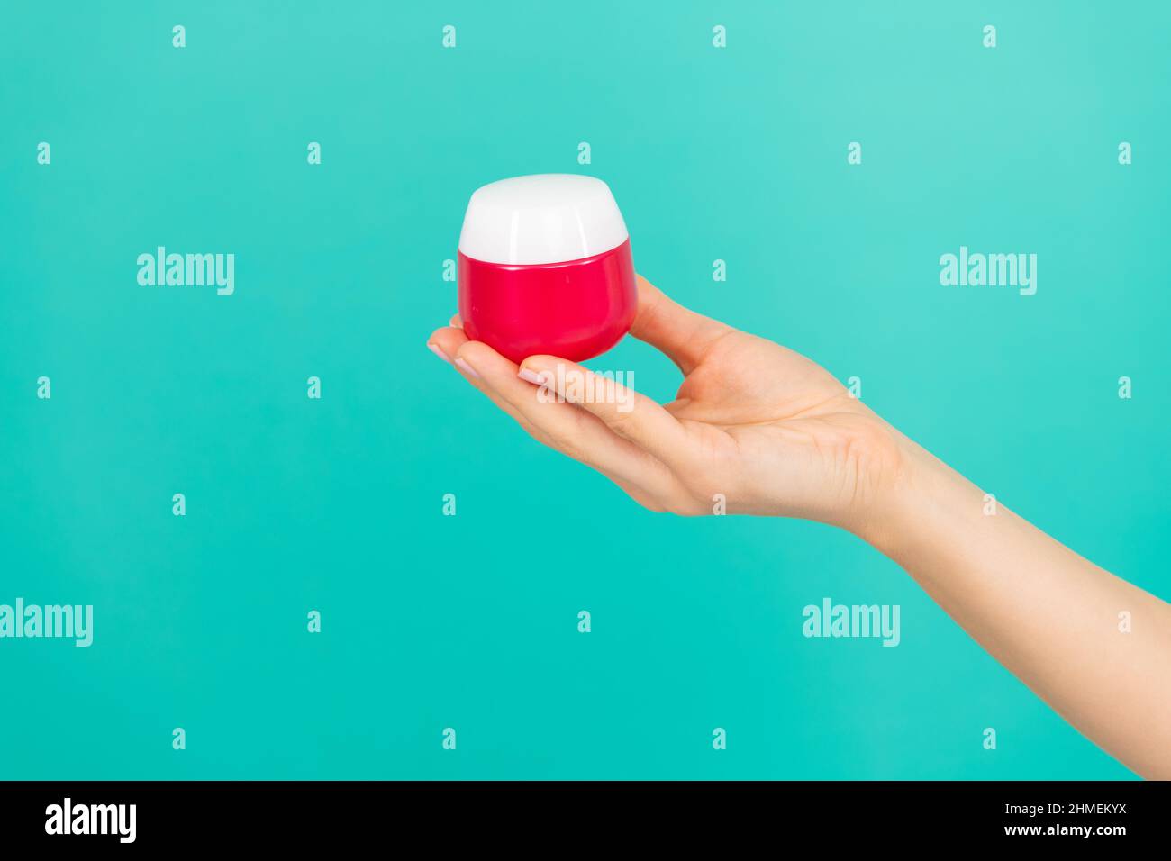 crema per la pelle di mantenimento femminile su sfondo blu Foto Stock