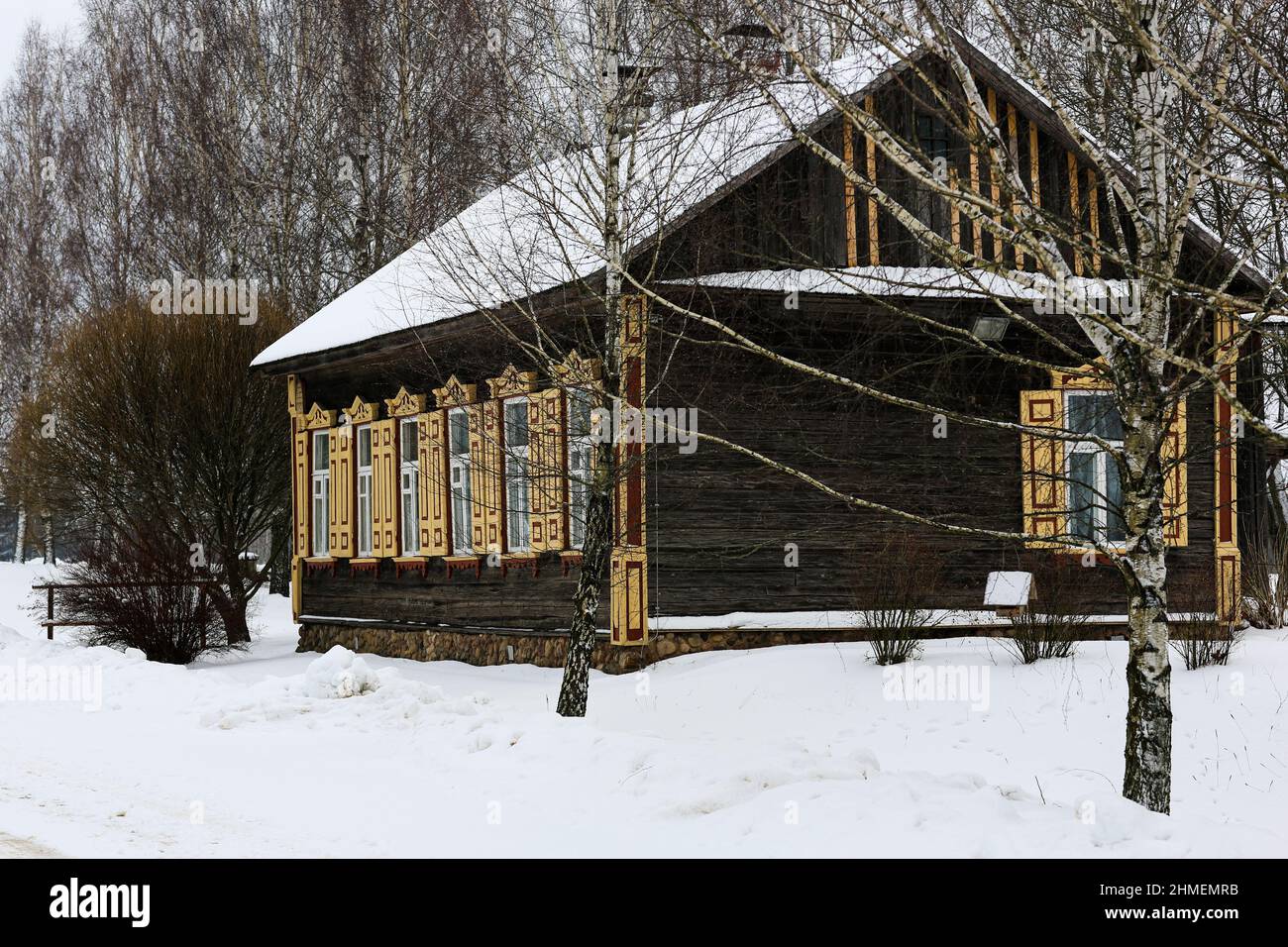 Vecchia casa in legno di tronchi grigi. Con belle finestre e persiane gialle. Foto Stock