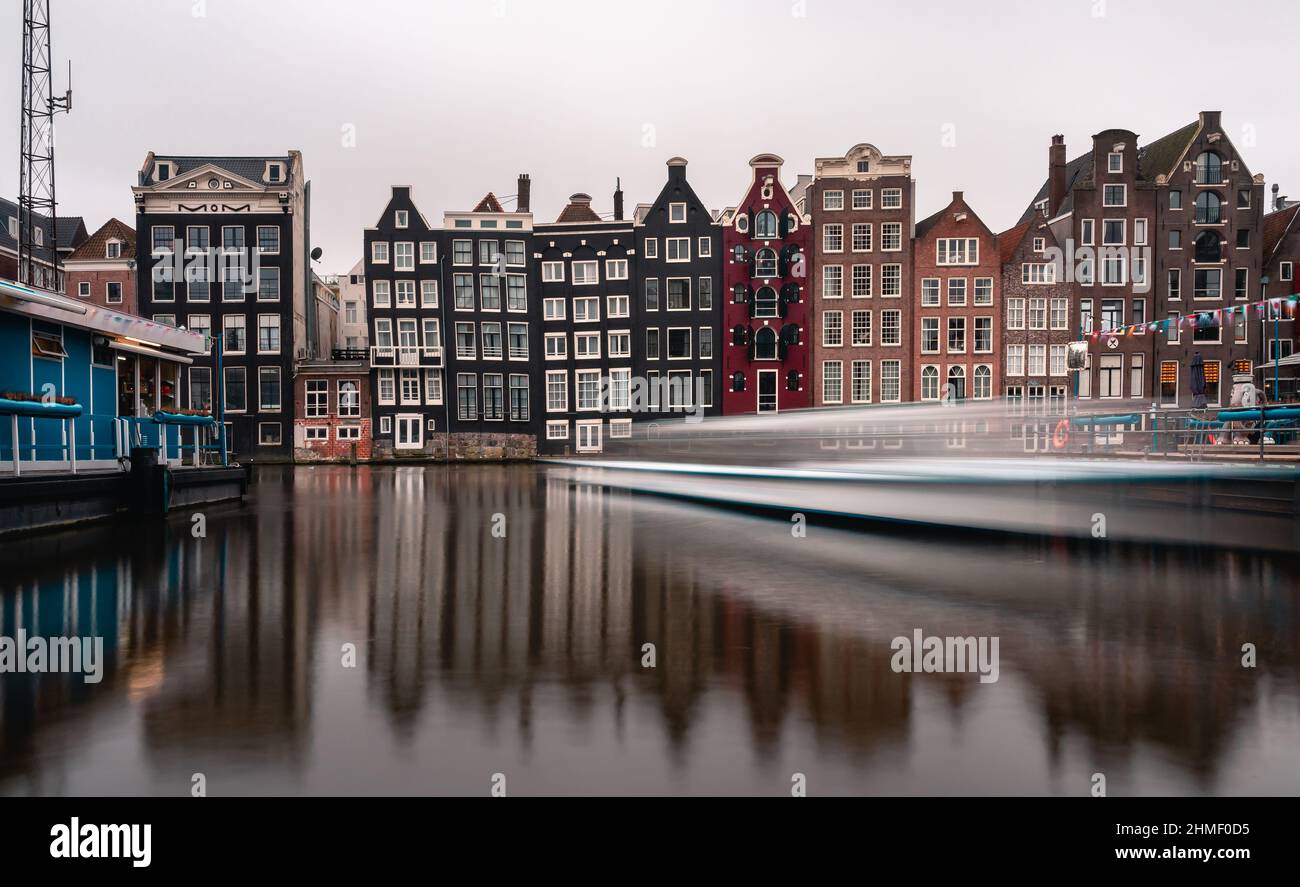 Vecchi edifici tradizionali ad Amsterdam, Paesi Bassi - barca turistica di passaggio Foto Stock