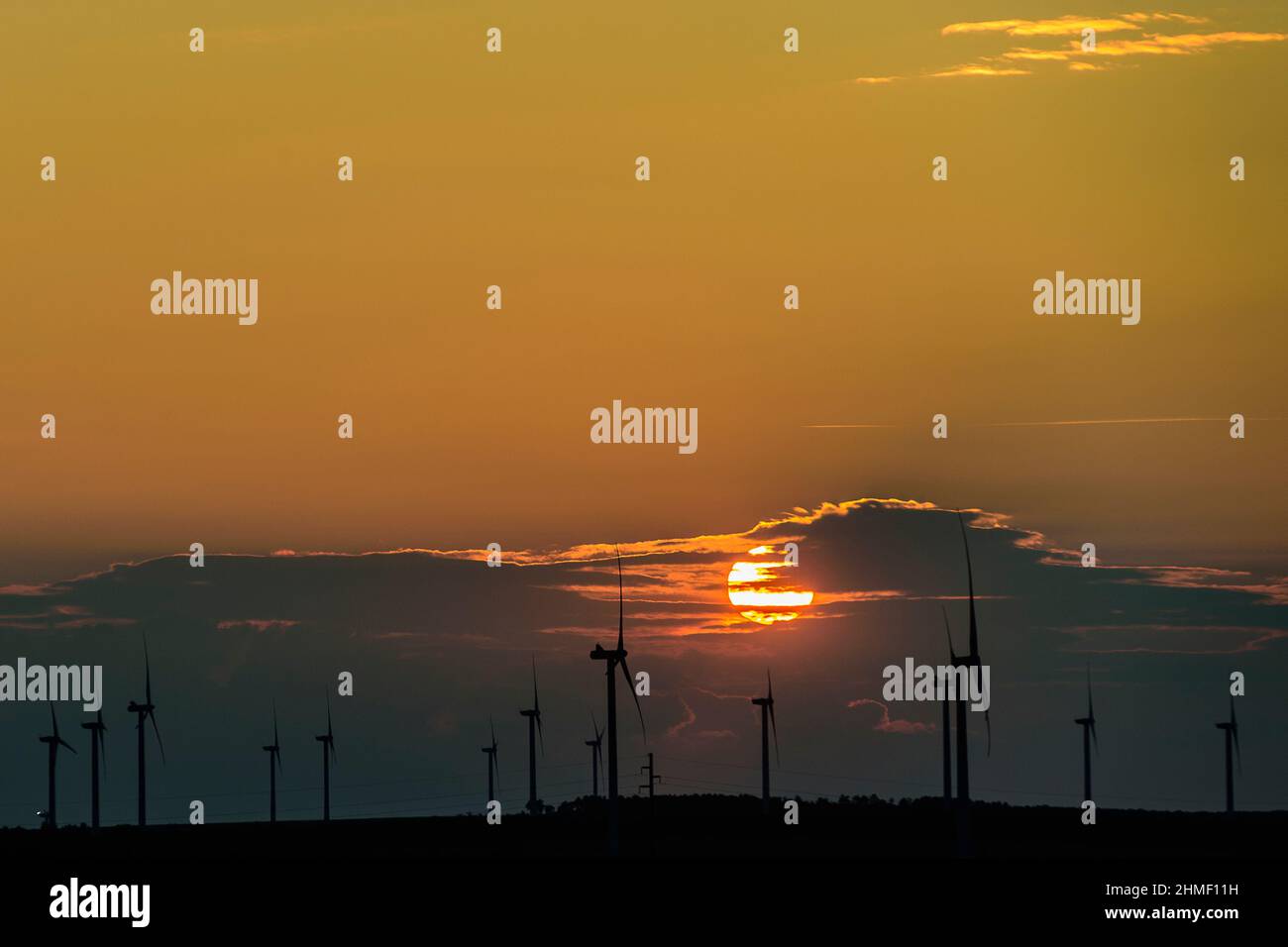 Tramonto su una fattoria di turbine eoliche nel mezzo dei campi. Rete elettrica con turbina eolica | Reseau electrique Canche de soleil sur un Champ d Foto Stock