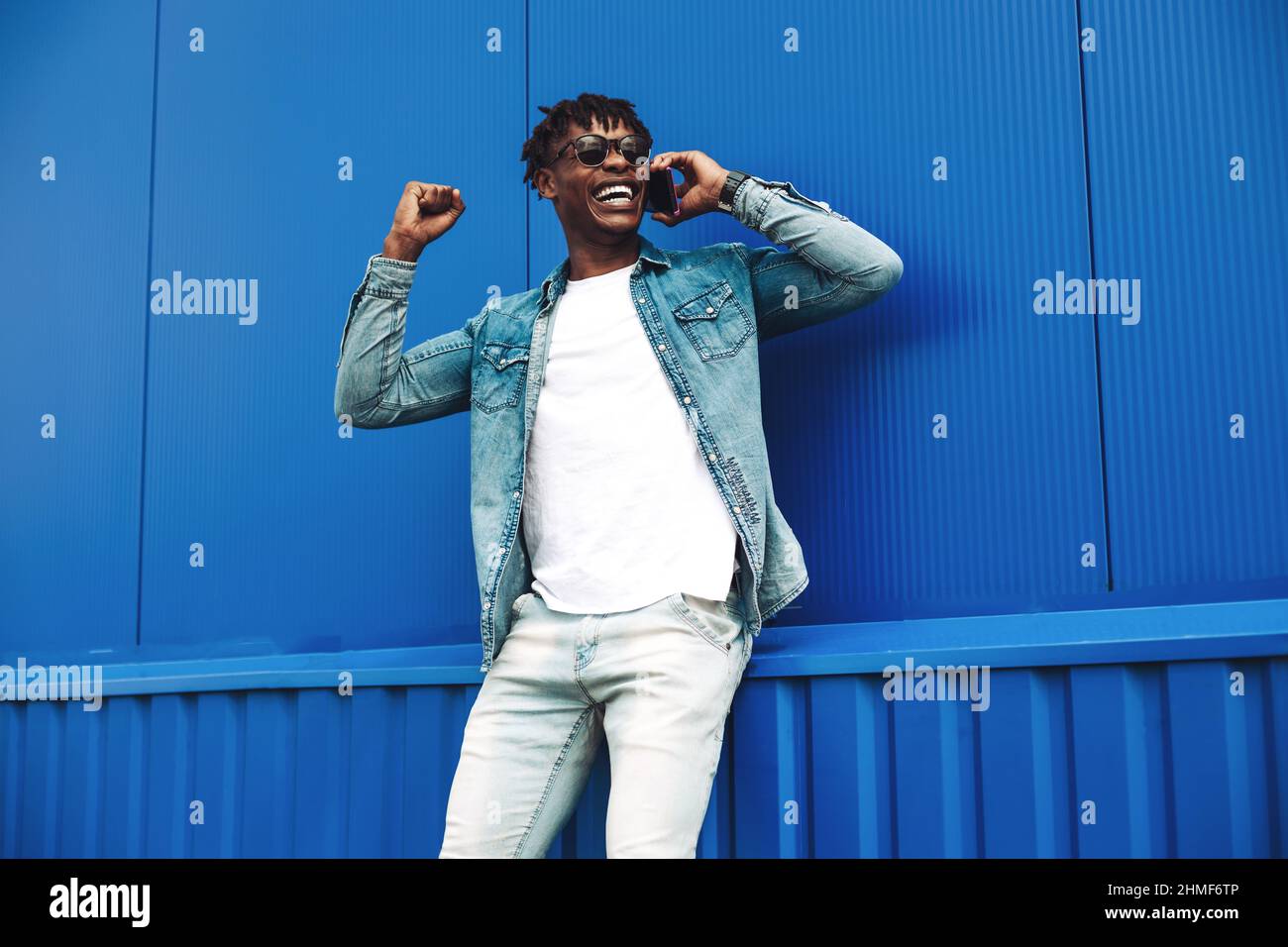 Primo piano di un uomo afroamericano che parla al telefono cellulare, che celebra il successo e la vittoria, mostrando sì gesto, uomo ricci capelli eccitati abo Foto Stock