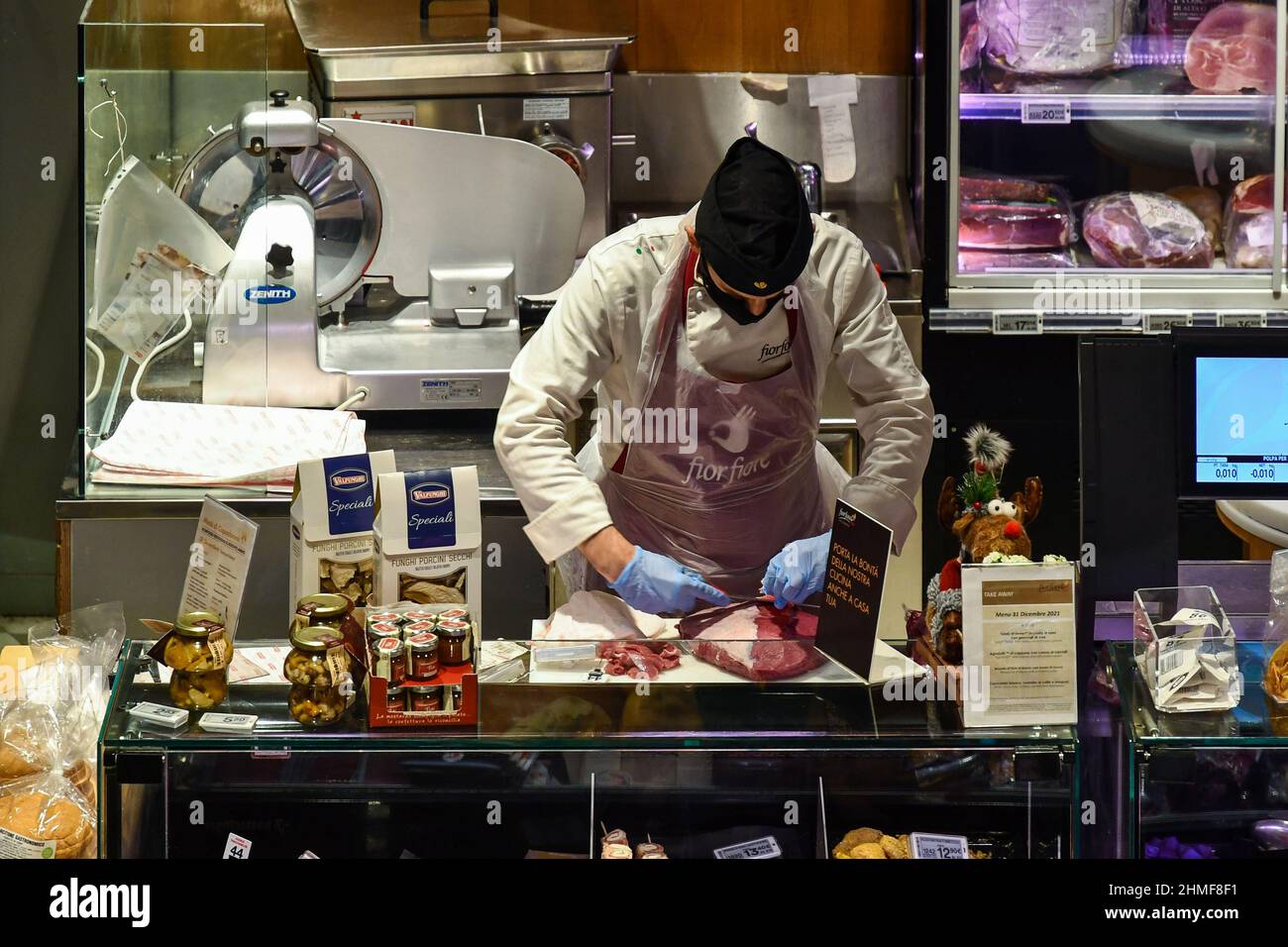 Un macellaio che prepara un taglio di carne al bancone del macellaio all'interno del negozio Coop Concept in Galleria San Federico, Torino, Piemonte, Italia Foto Stock