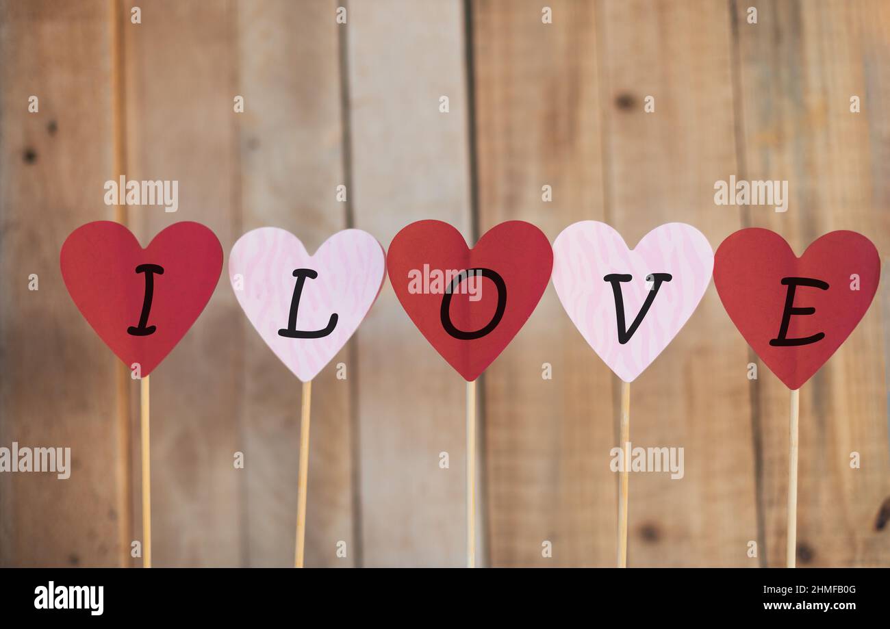 cuori di colore rosso e rosa con la parola che ti amo su sfondo di legno, san valentino Foto Stock