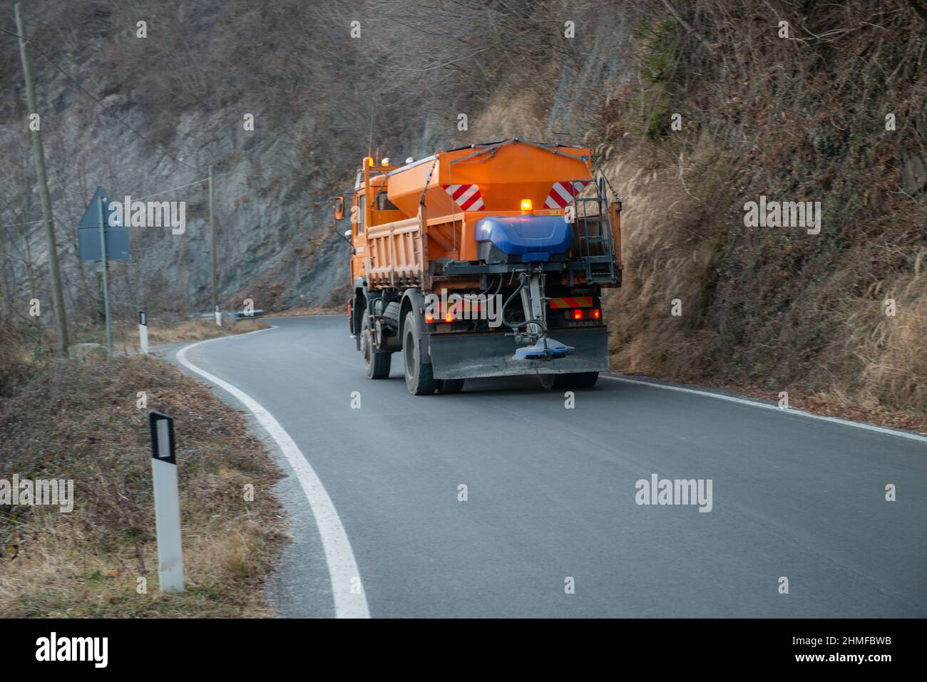 Veicolo che sparge il sale su una strada tortuosa Foto Stock