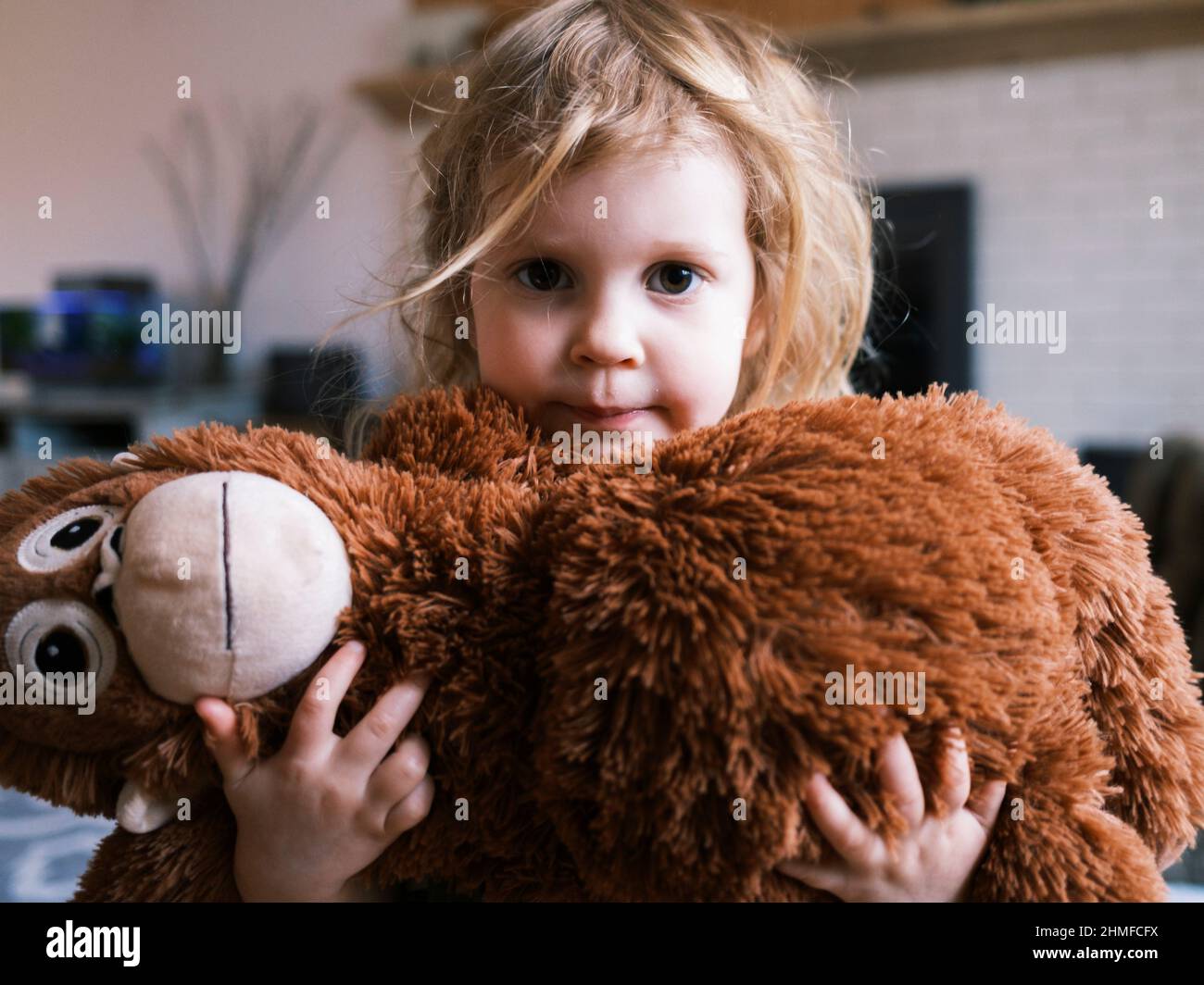Giovane ragazza che tiene un giocattolo scimmia nel soggiorno Foto Stock