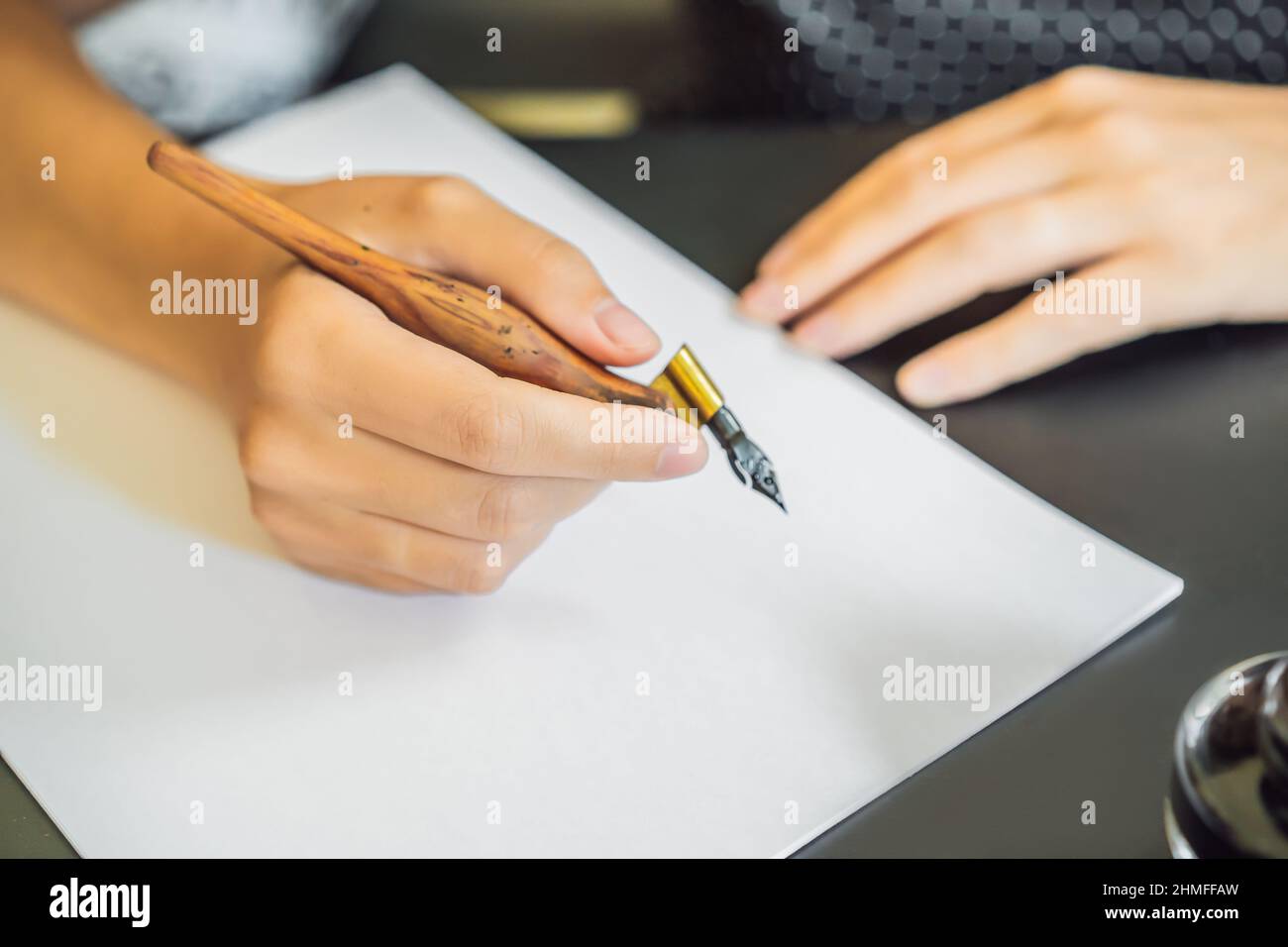 Calligrapher giovane donna scrive una frase sul libro bianco. Inscrivendo ornamentali in lettere decorate. La calligrafia, graphic design, scritte, la grafia Foto Stock