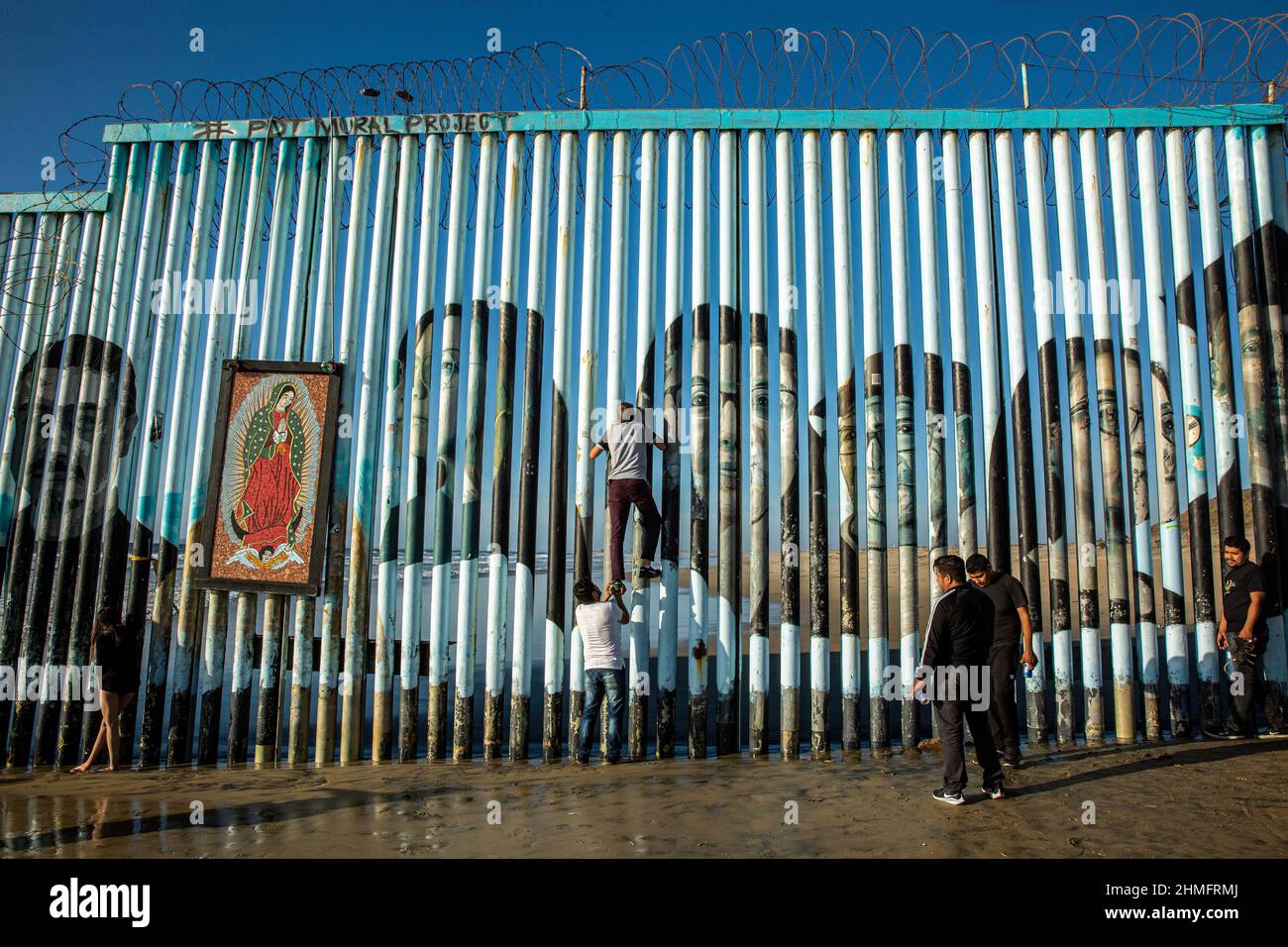 Un uomo ha visto salire il muro che divide il Messico dagli Stati Uniti a Tijuana Beach. Foto Stock Un uomo ha visto salire il muro che divide il Messico dagli Stati Uniti a Tijuana Beach. Foto Stock