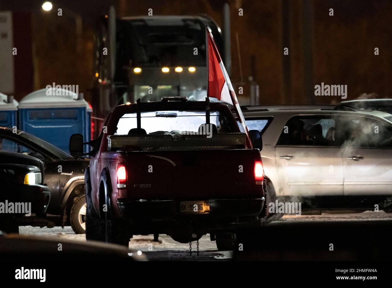Un camion di pick up che vola la bandiera canadese in protesta idles nel centro di notte come parte del blocco anti-mandato e l'occupazione di Ottawa. Foto Stock