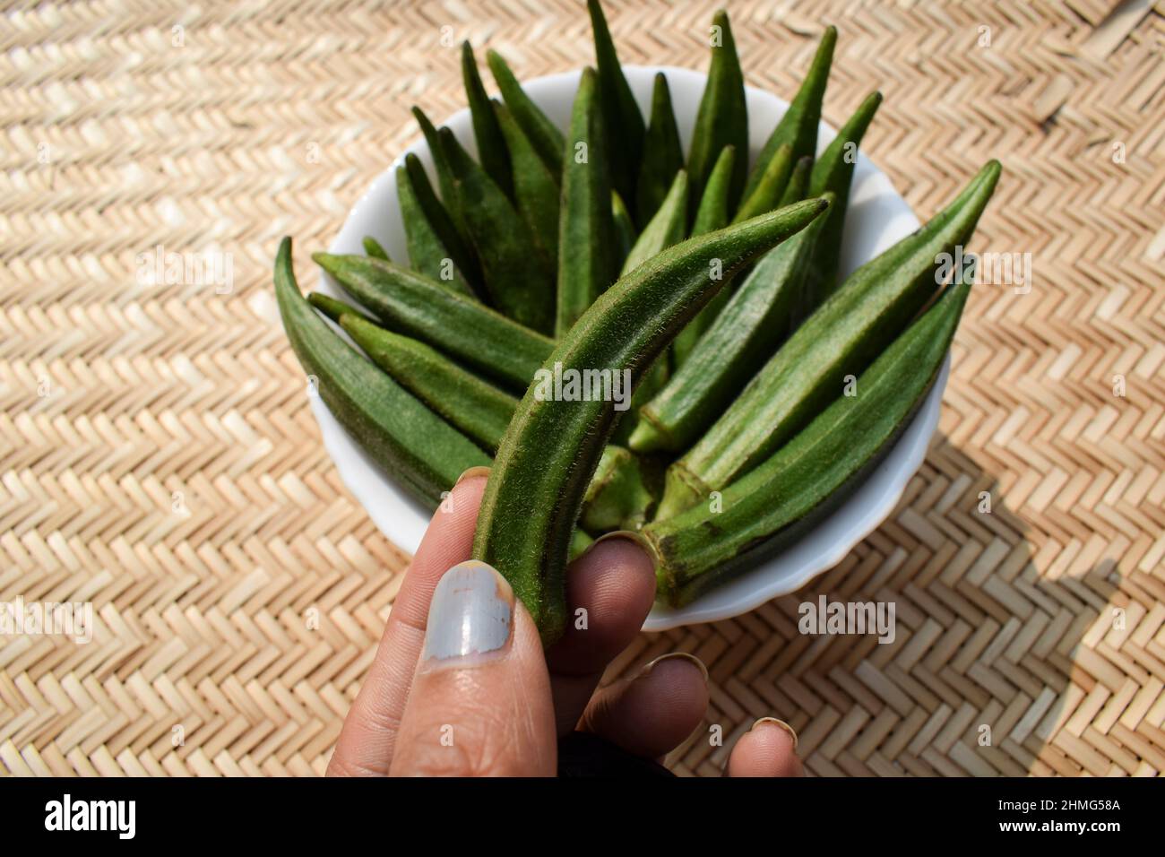 Donna che tiene fresco Okra vegetali o verdure verdi Lady dito o savoiardi anche noto come Bhindi in hindi e urdu. Foto Stock