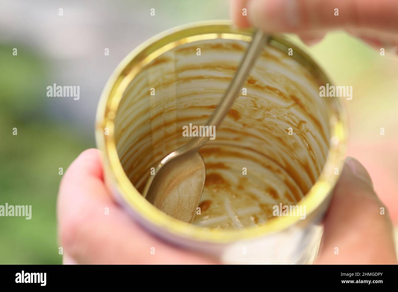 Una lattina di caramello è stato raschiato da un cucchiaino da tè per ottenere gli ultimi bocconcini gustosi fuori, i contenuti sono andati in una torta di banoffee Foto Stock