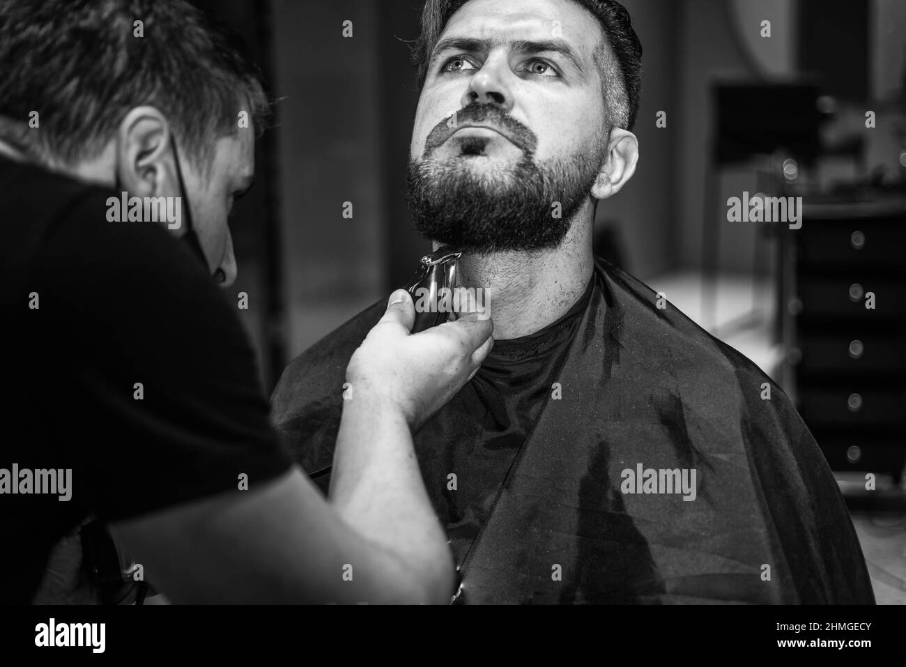 L'aspetto era perfetto. L'hipster brutale con baffi rende nuovi i capelli. Barbiere. Capelli alla moda maschile. Taglio perfetto con rasoio a lama. taglio barber Foto Stock