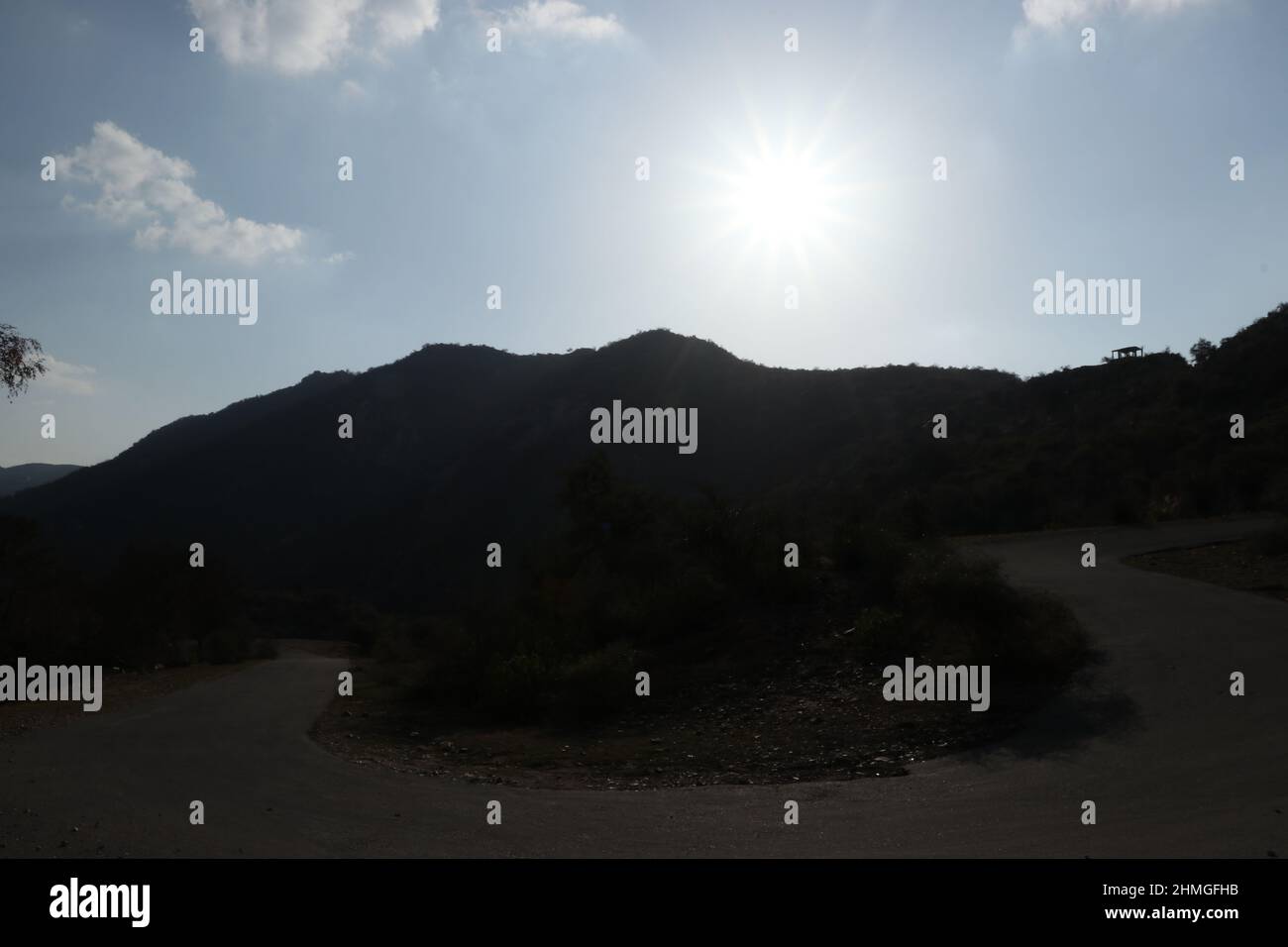 sole dietro la montagna con cielo blu. Foto Stock