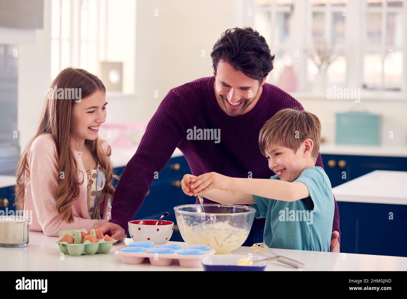 Padre con due bambini in cucina a casa che hanno dolci da forno divertenti insieme Foto Stock