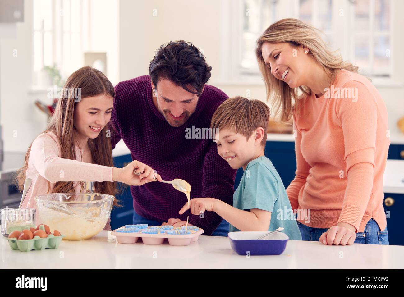 Famiglia con due bambini in cucina a casa avendo Fun torte da forno insieme Foto Stock