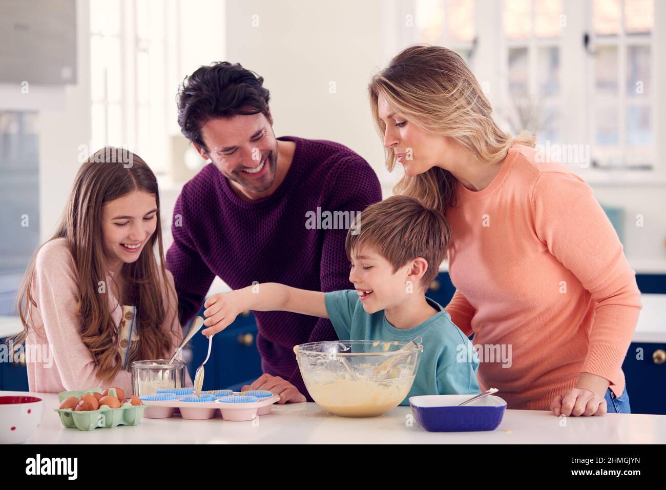 Famiglia con due bambini in cucina a casa avendo Fun torte da forno insieme Foto Stock