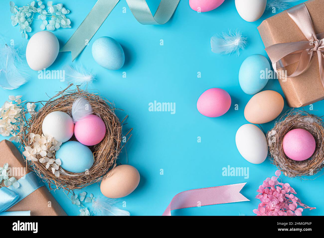 Buona Pasqua, delicato, sfondo pastello con uova colorate, scatole regalo e nidi su sfondo blu. Vista dall'alto, spazio di copia. Foto Stock