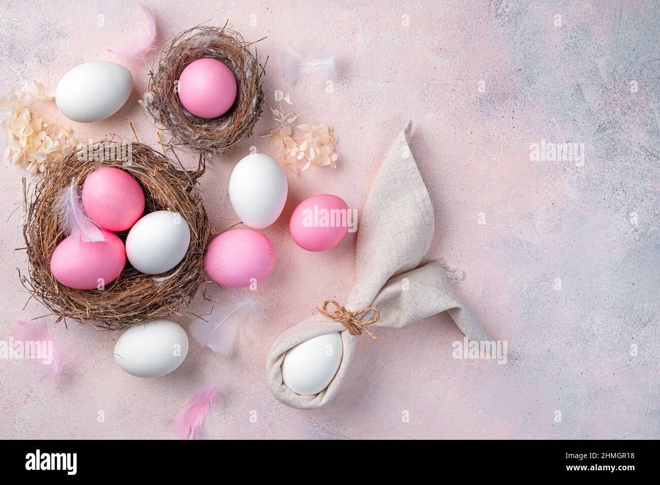 Buona Pasqua, un pastello sfondo festivo con uova bianche e rosa e un coniglietto pasquale da un tovagliolo. Vista dall'alto, spazio di copia. Foto Stock