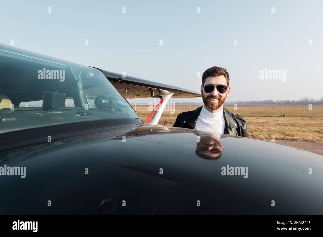 pilota sorridente in giacca di pelle e occhiali da sole vicino all'aereo  Foto stock - Alamy