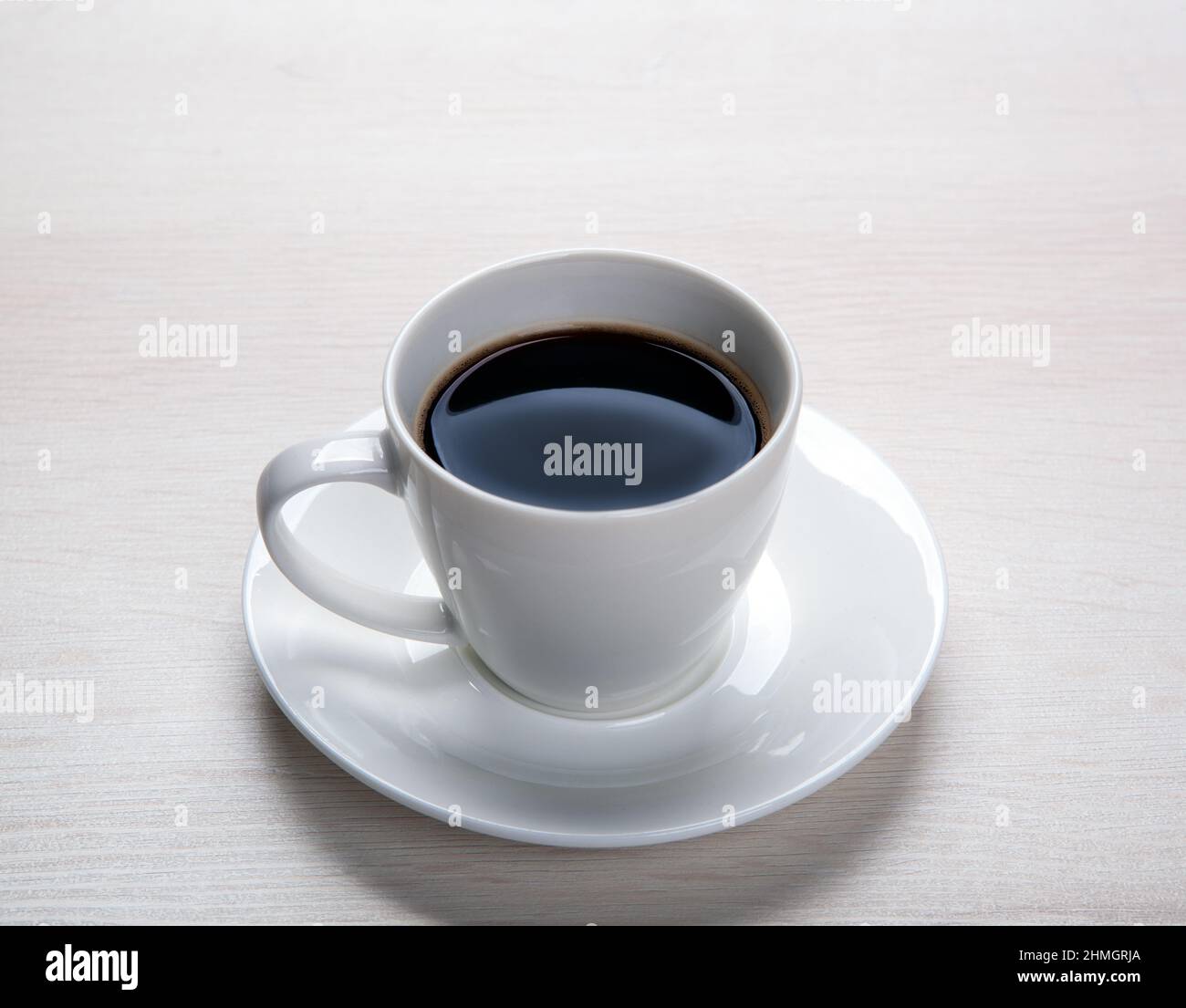 tazza bianca con caffè nero e piattino sul piano del tavolo Foto Stock