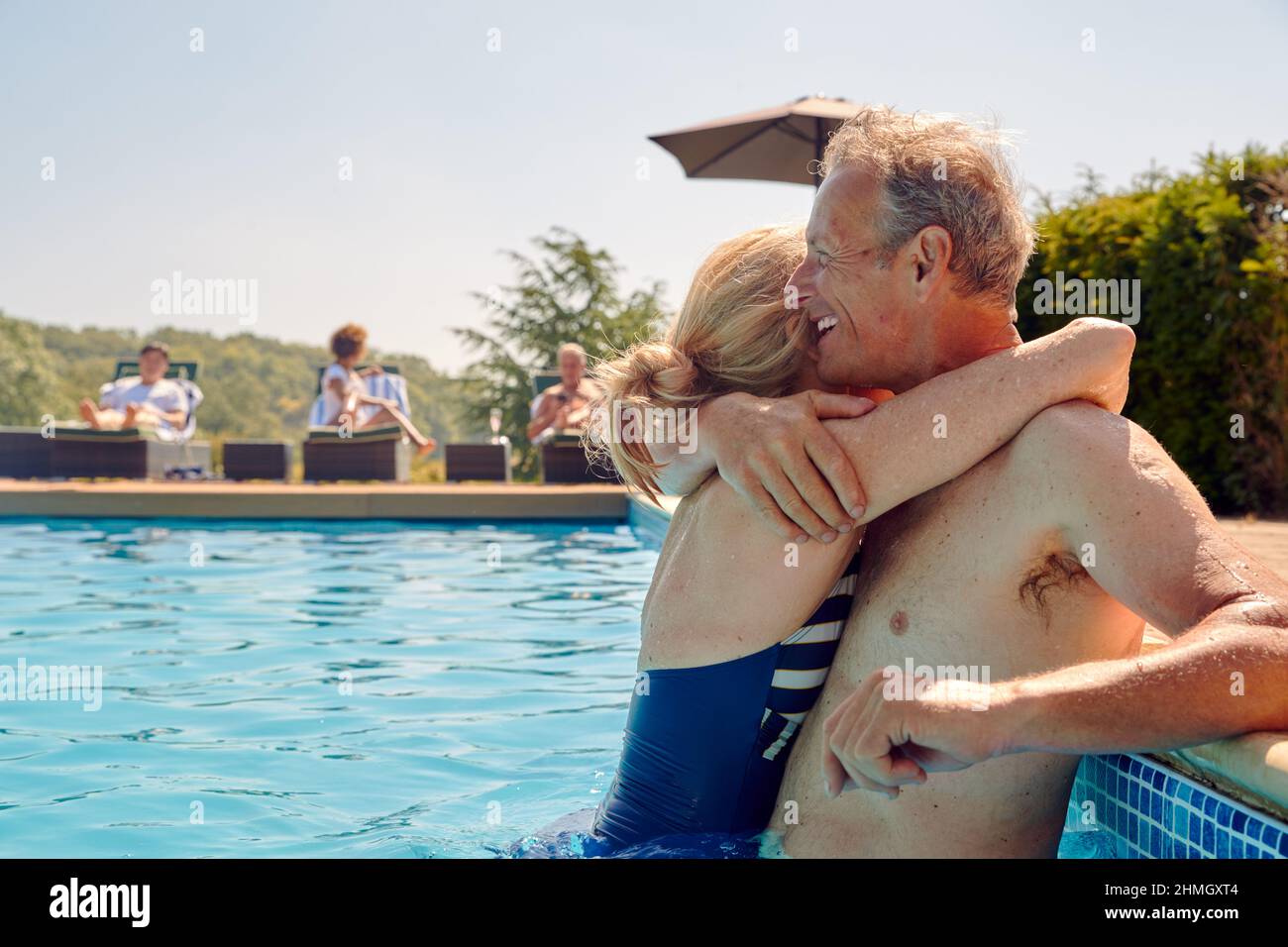 Amorevole coppia anziano pensionato che abbraccia a lato della piscina durante la vacanza estiva Foto Stock
