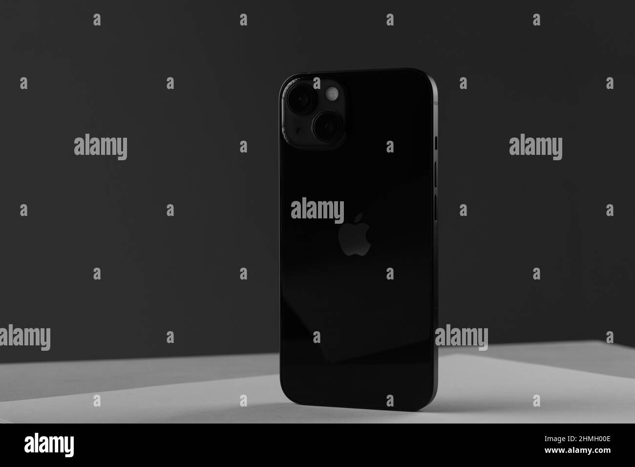 Nuovo telefono cellulare moderno iPhone 13 di colore nero contro una parete grigia Foto Stock