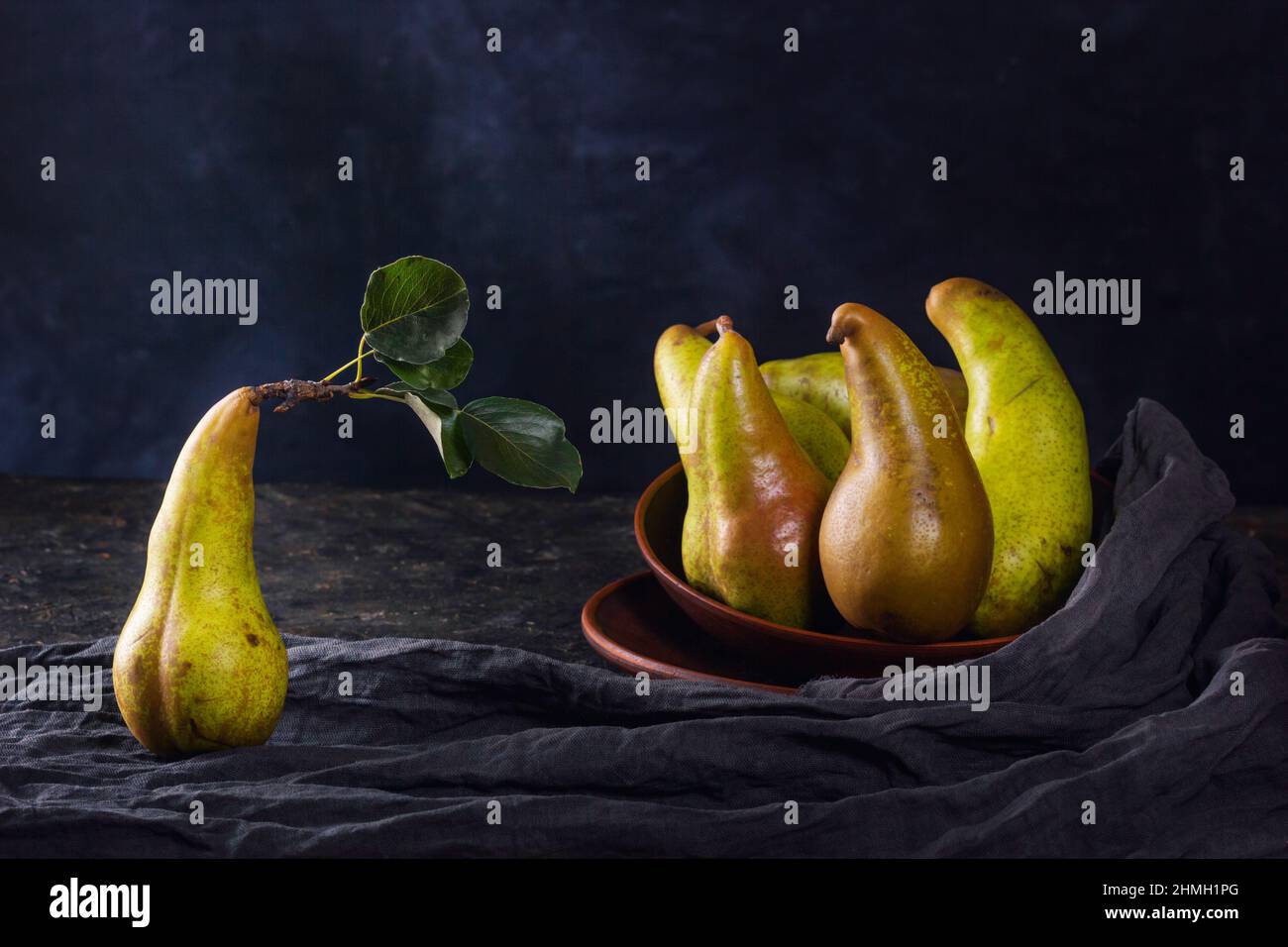 Vita rurale morta, fotografia oscura a basso tasto - vista di una conferenza pera in piatti di argilla, primo piano con fuoco selettivo Foto Stock