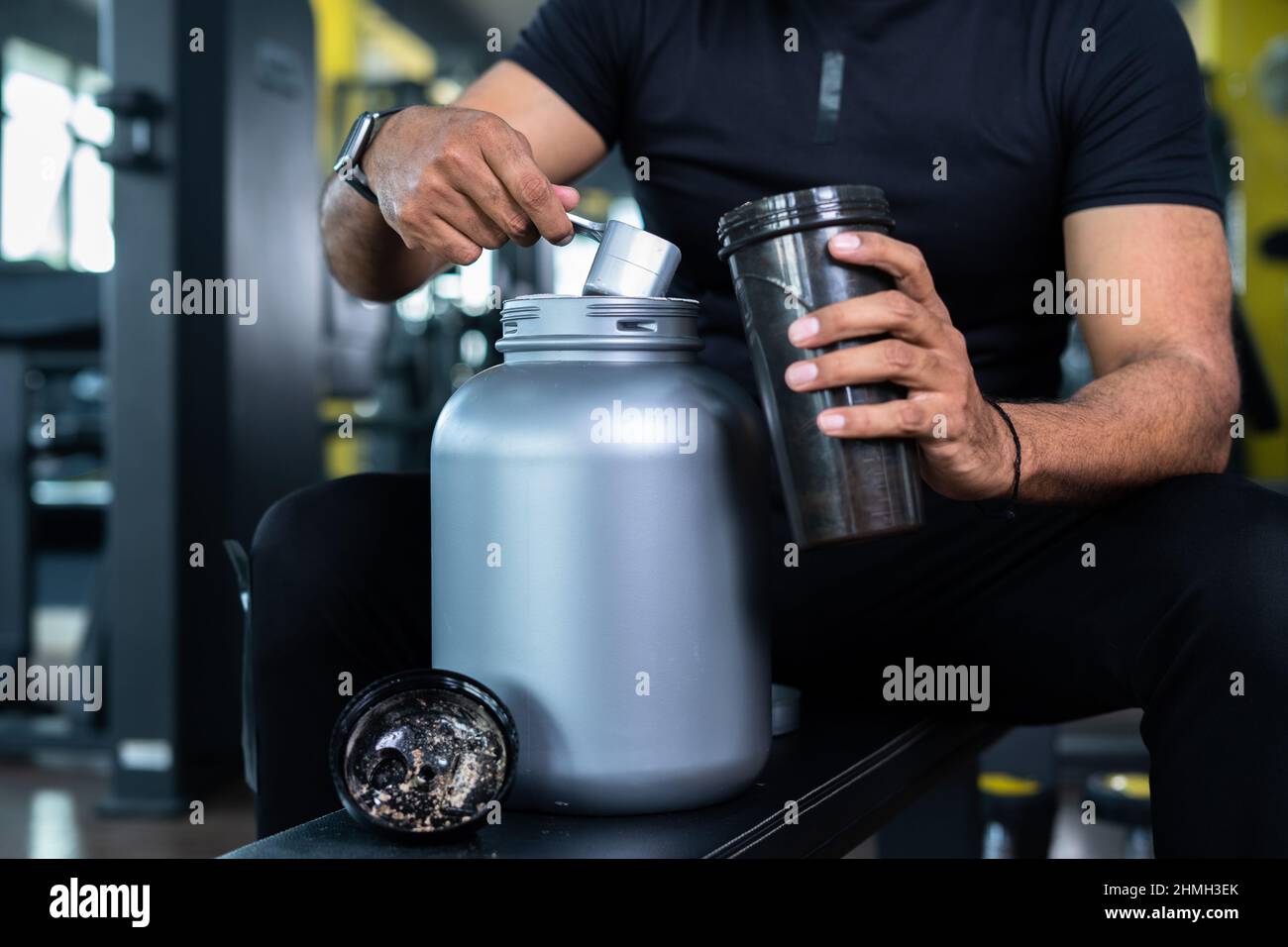 primo piano di mani bodybuilder prendendo proteine in polvere e mescolando con acqua in bottiglia scuotendo in palestra - concpet di guadagno muscolare, nutrizionale Foto Stock
