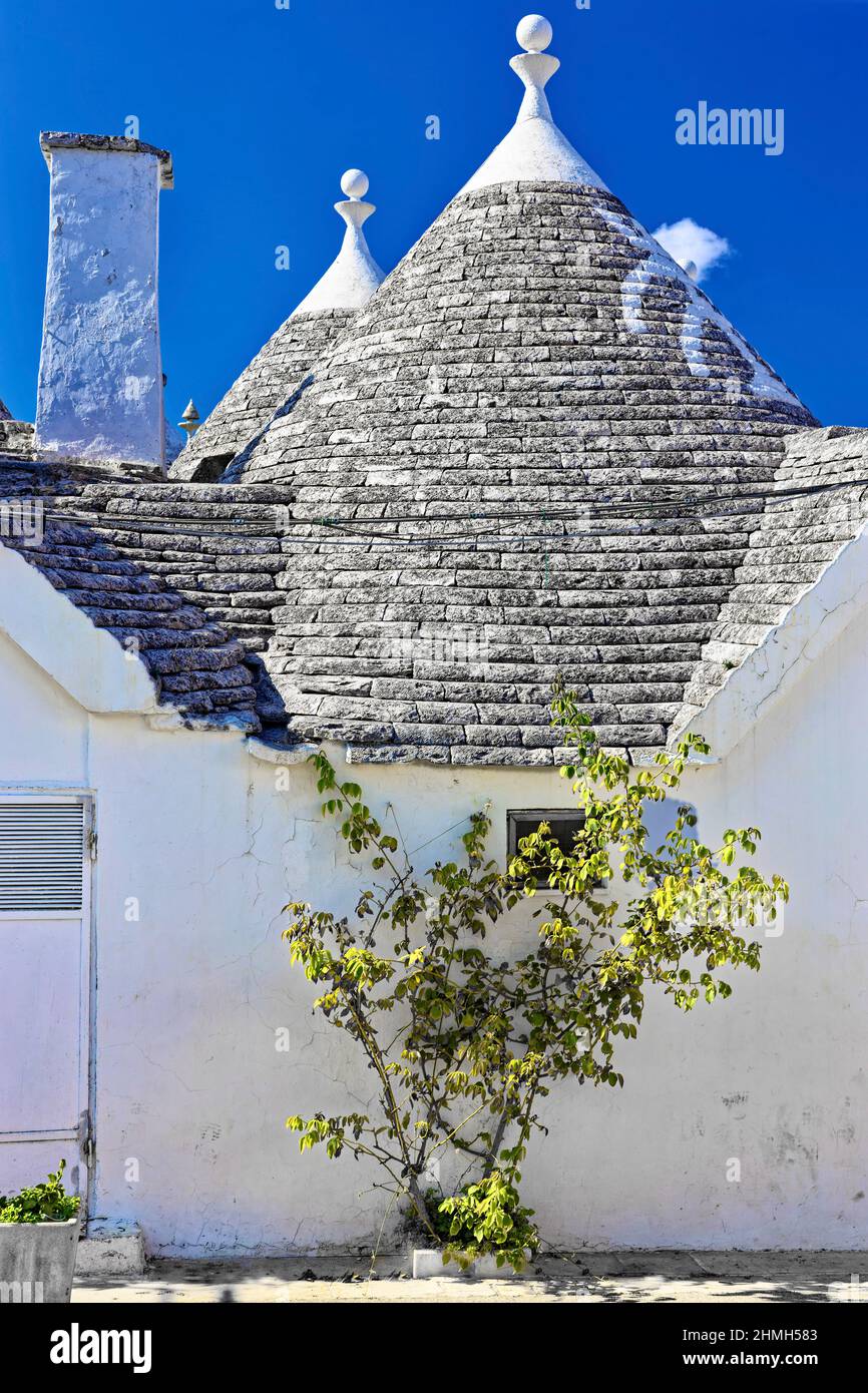 Trulli in Alberobello, Puglia, Italia sotto un cielo blu Foto Stock