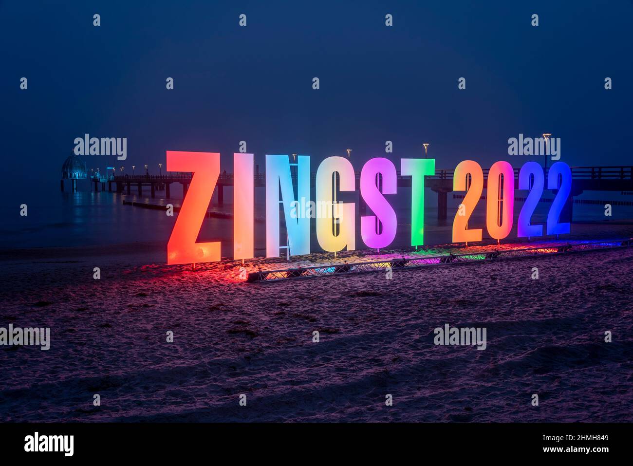 Germania, Meclemburgo-Pomerania occidentale, Zingst, scritta 'Zingst 2022' fatta di lettere illuminate, dietro il molo della località del Mar Baltico Foto Stock