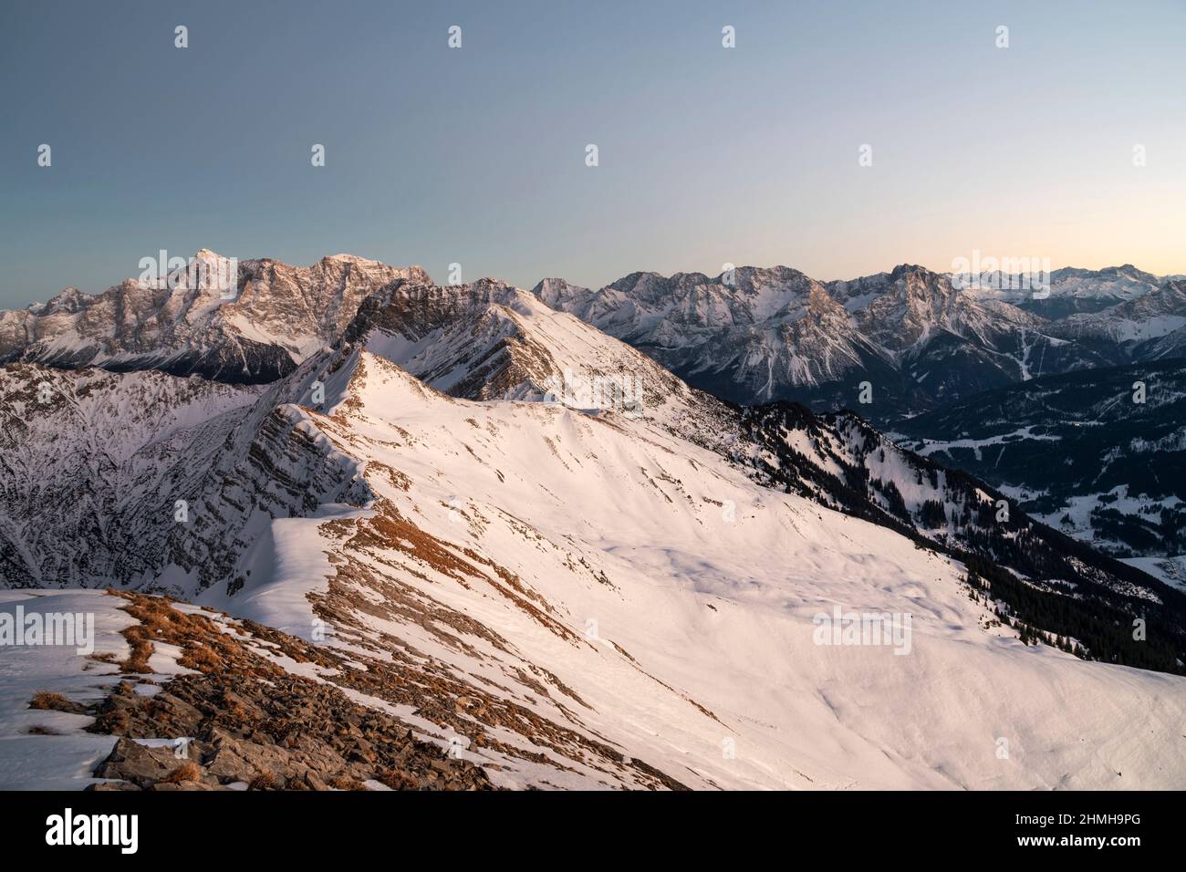 Paesaggio alpino di montagna in un freddo giorno invernale dopo il tramonto. Vista dalla Hochschrutte (Alpi Ammergau) alle Zugspitze e alla catena Mieminger. Tirolo, Austria, Europa Foto Stock