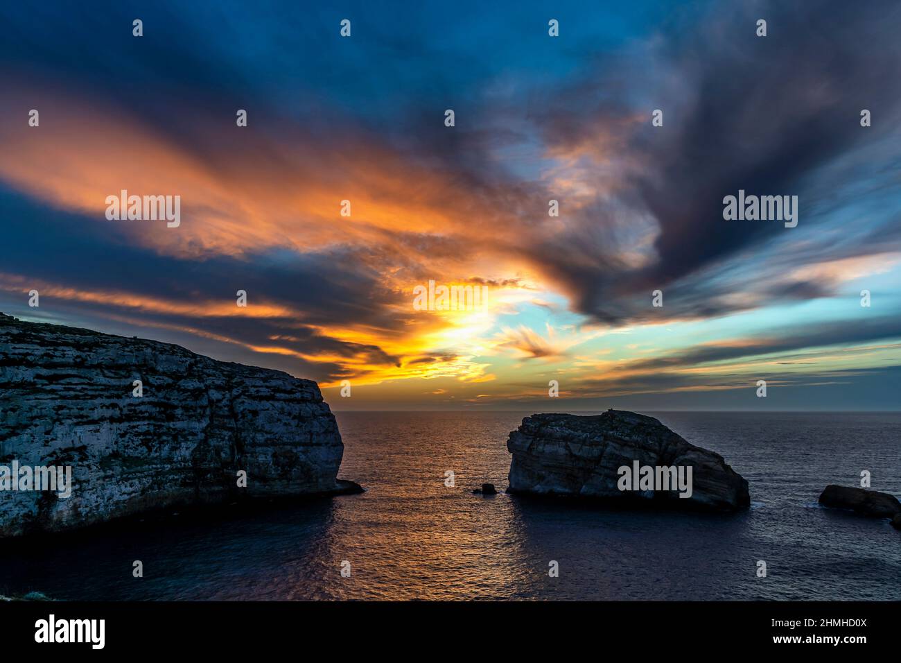 Il sole tramonta in colori gloriosi sulla Baia di Dwejra a Gozo Foto Stock