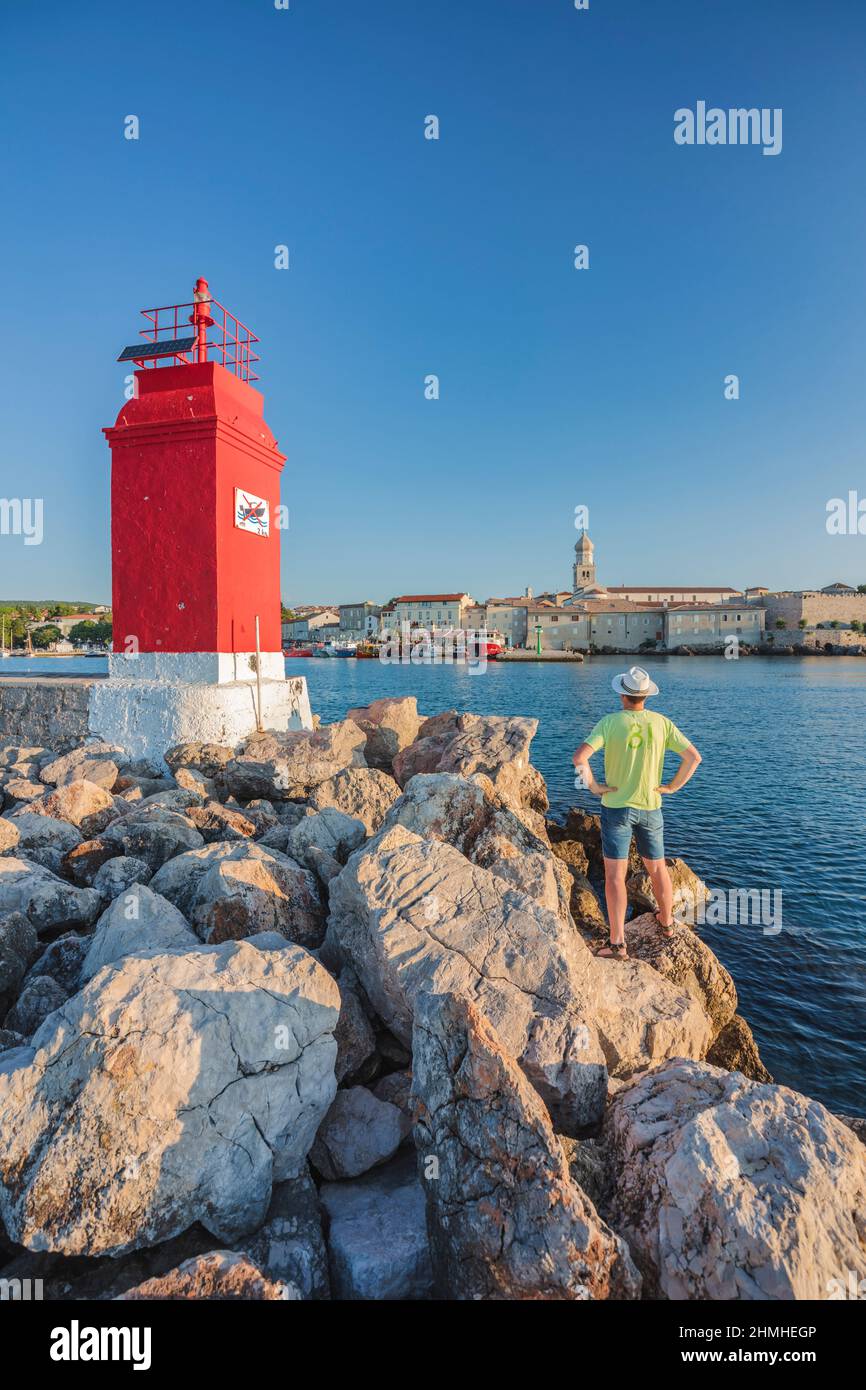 Croazia, baia di Kvarner, isola di Krk, turista vicino al faro rosso all'ingresso del porto di Krk Foto Stock