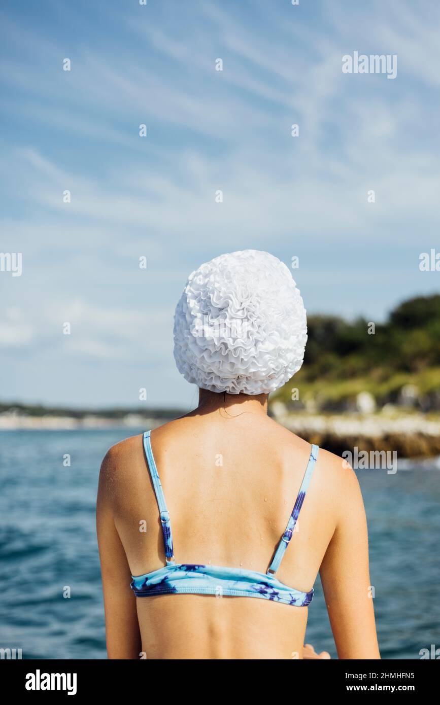 Vista posteriore di una persona femminile in un bikini e cappellino da nuoto al mare Foto Stock