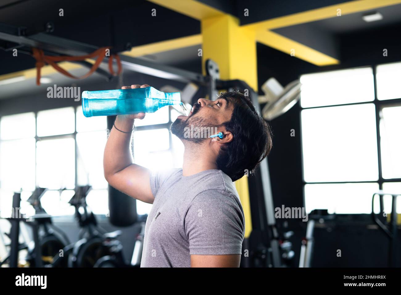 Assetato giovane musclebuilder indiano bere acqua dopo l'allenamento in palestra - concetto di relax, stili di vita sani e duro allenamento o fitness Foto Stock