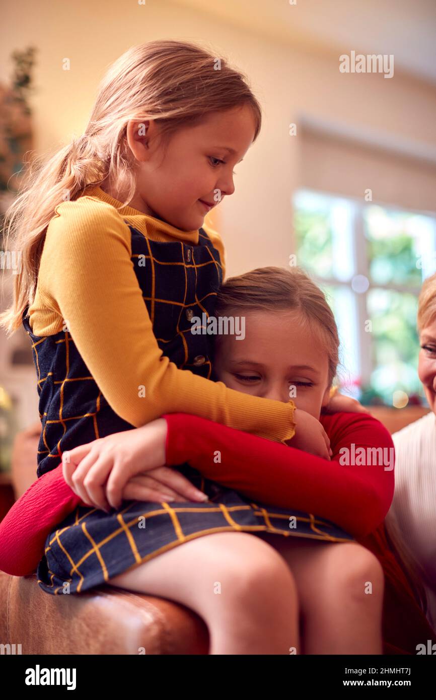 Due suore abbracciano come famiglia Multi-Generation Open Gifts intorno all'albero di Natale a casa Foto Stock