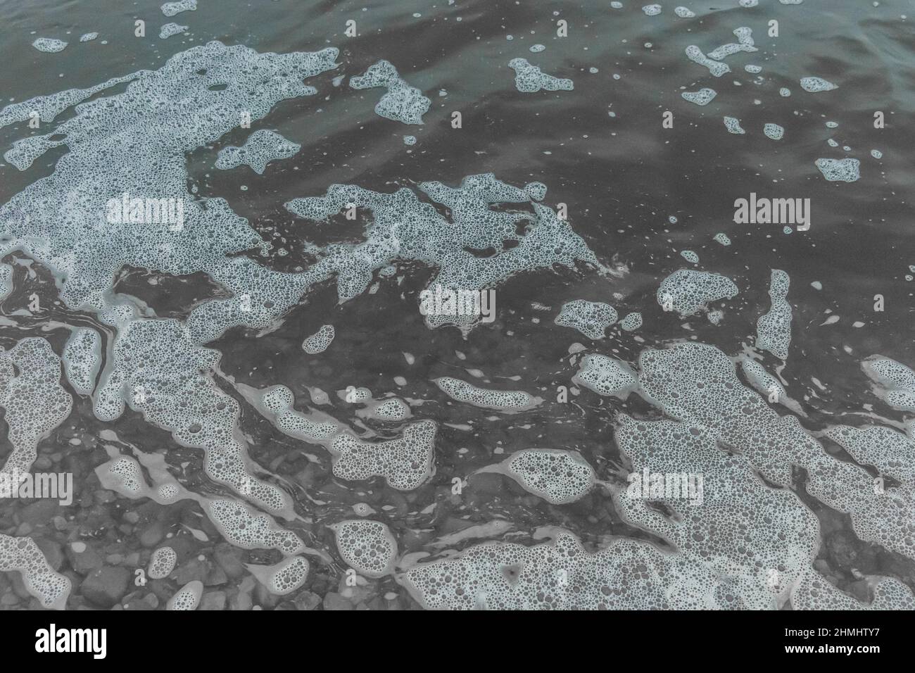 White foam astratto naturale schiumoso motivo sulla superficie del lago d'acqua fondo texture. Foto Stock
