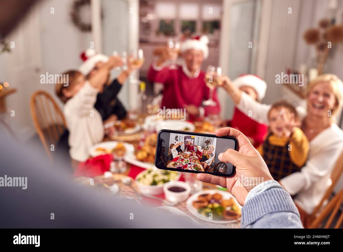 POV colpo di persona che prende la foto del pasto della famiglia di Multi-generazione a Natale sul telefono mobile Foto Stock