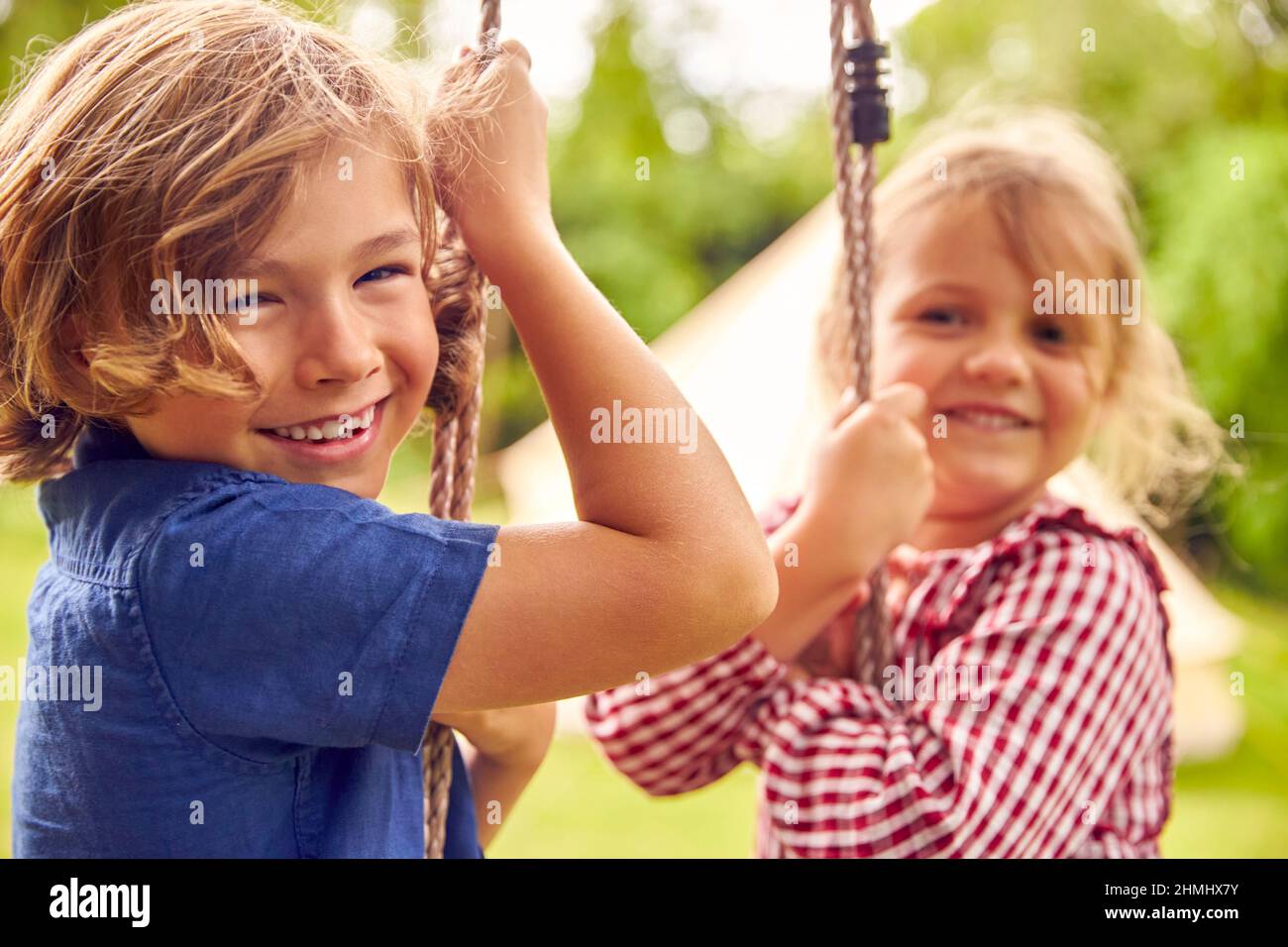 Ritratto di due bambini che giocano a Swing in Garden at Home Foto Stock