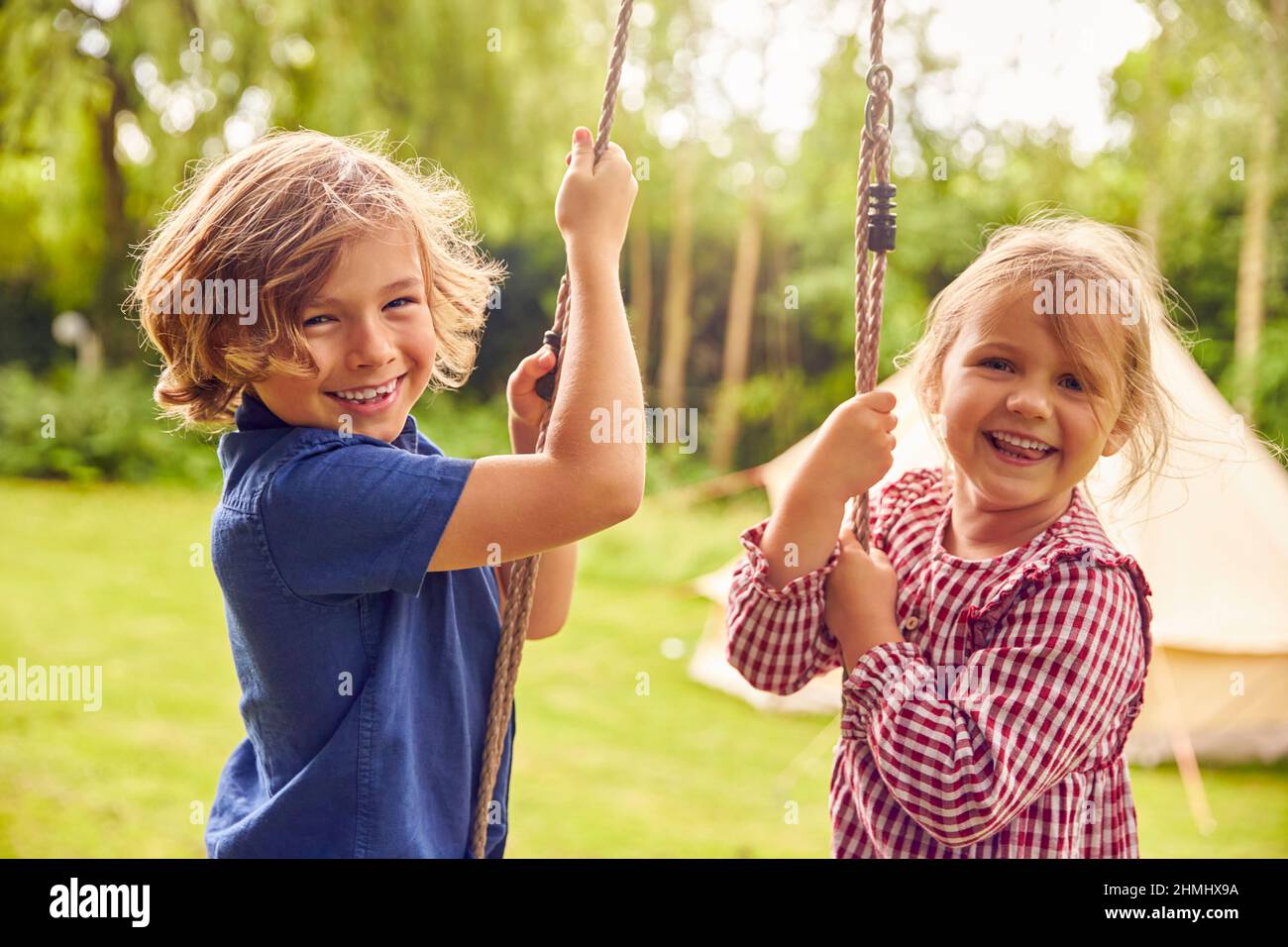 Ritratto di due bambini che giocano a Swing in Garden at Home Foto Stock