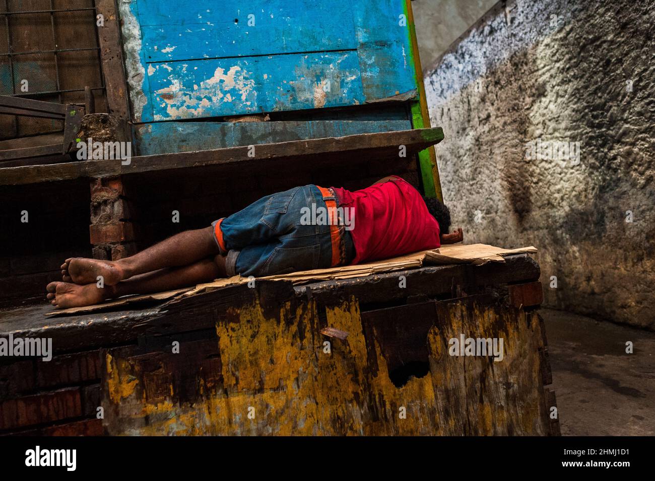 Un uomo senza casa afro-colombiano dorme sul cartone nel mercato di Bazurto, Cartagena, Colombia. Foto Stock