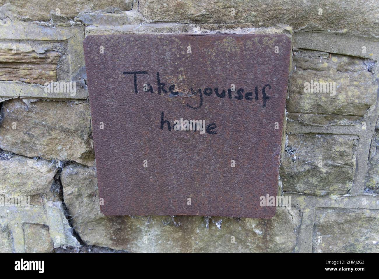 Un pezzo stravagante di graffiti recita, "Take Yourself Home", su una piastra metallica arrugginita posta in un muro a Jesmond, Newcastle upon Tyne, Regno Unito. Foto Stock