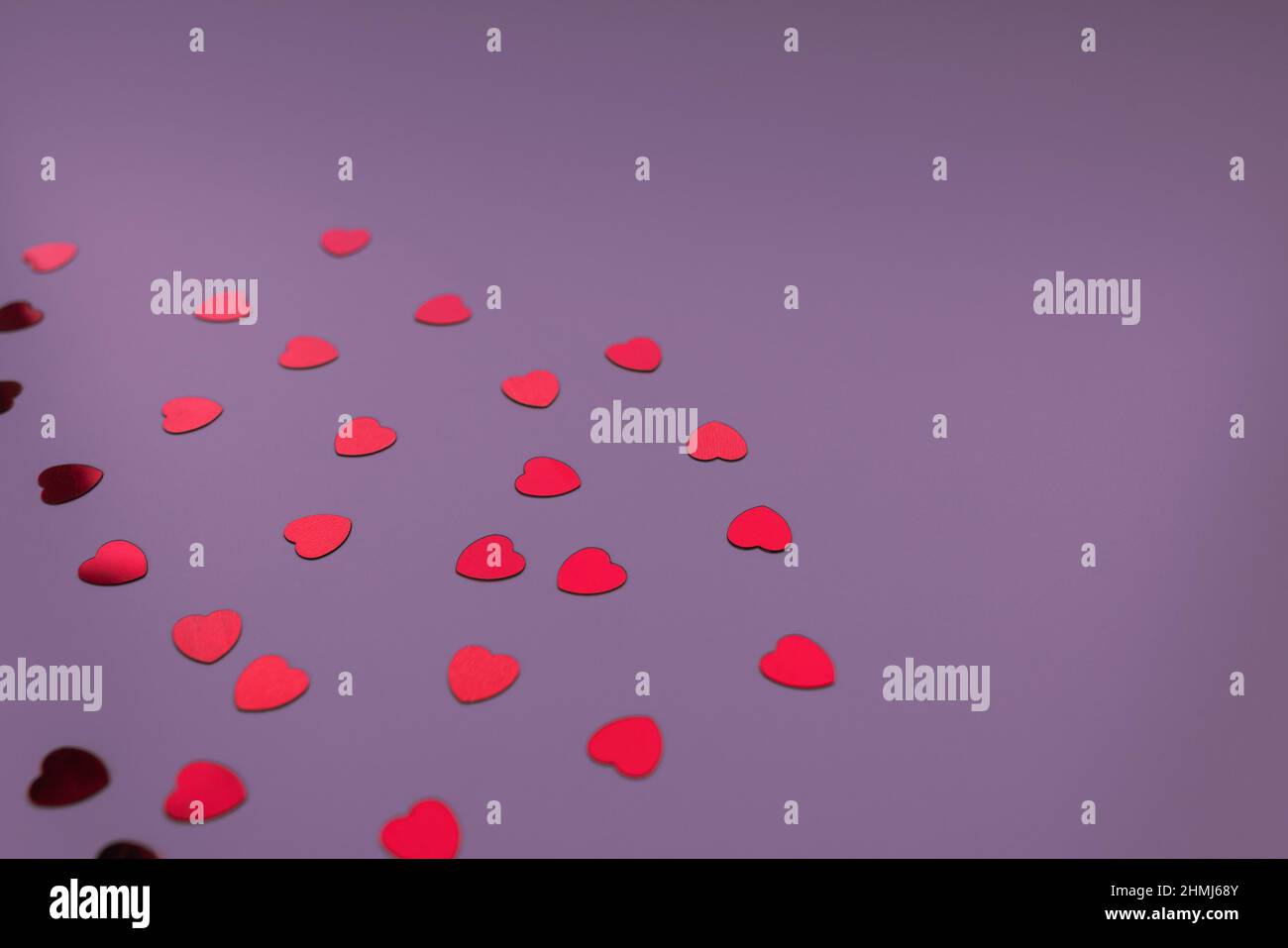 I cuori rossi si confettano su sfondo natalizio viola al neon. Amore, datazione e San Valentino concetto. Messa a fuoco selettiva, spazio di copia Foto Stock
