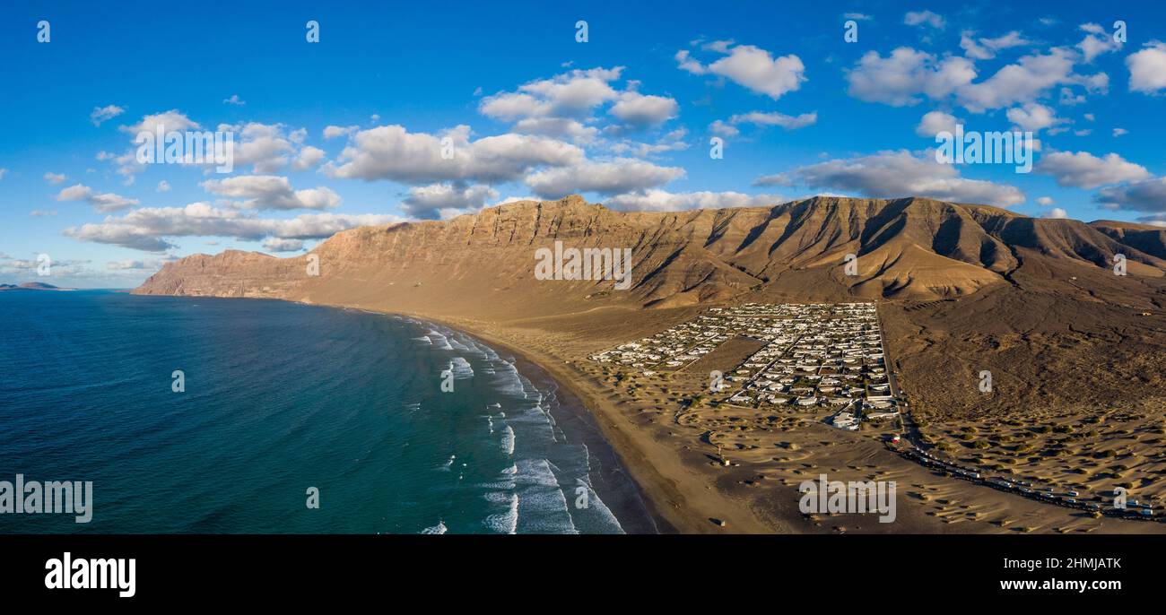 Famara villaggio e spiaggia con Risco de Famara montagne sullo sfondo, Spagna Foto Stock